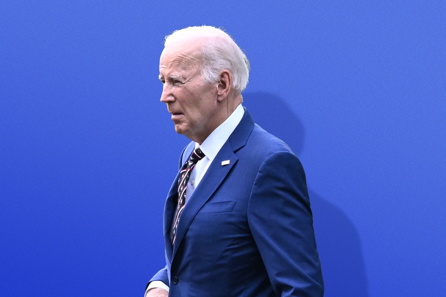 Joe Biden strolling determinedly in a blue suit and red-white-and-blue tie.