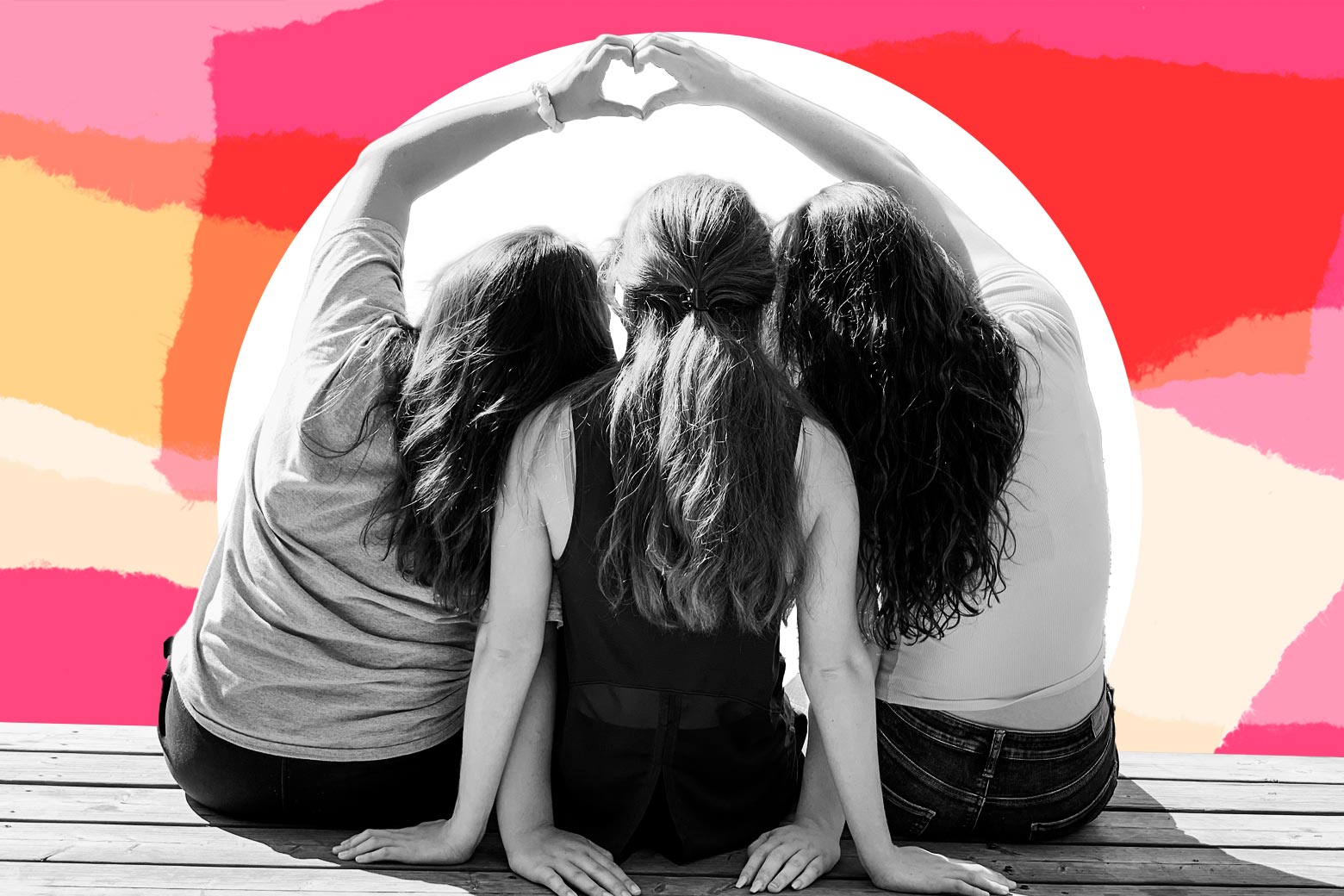Three girls sit on a dock with the girls on the left and right making a heart with their hands
