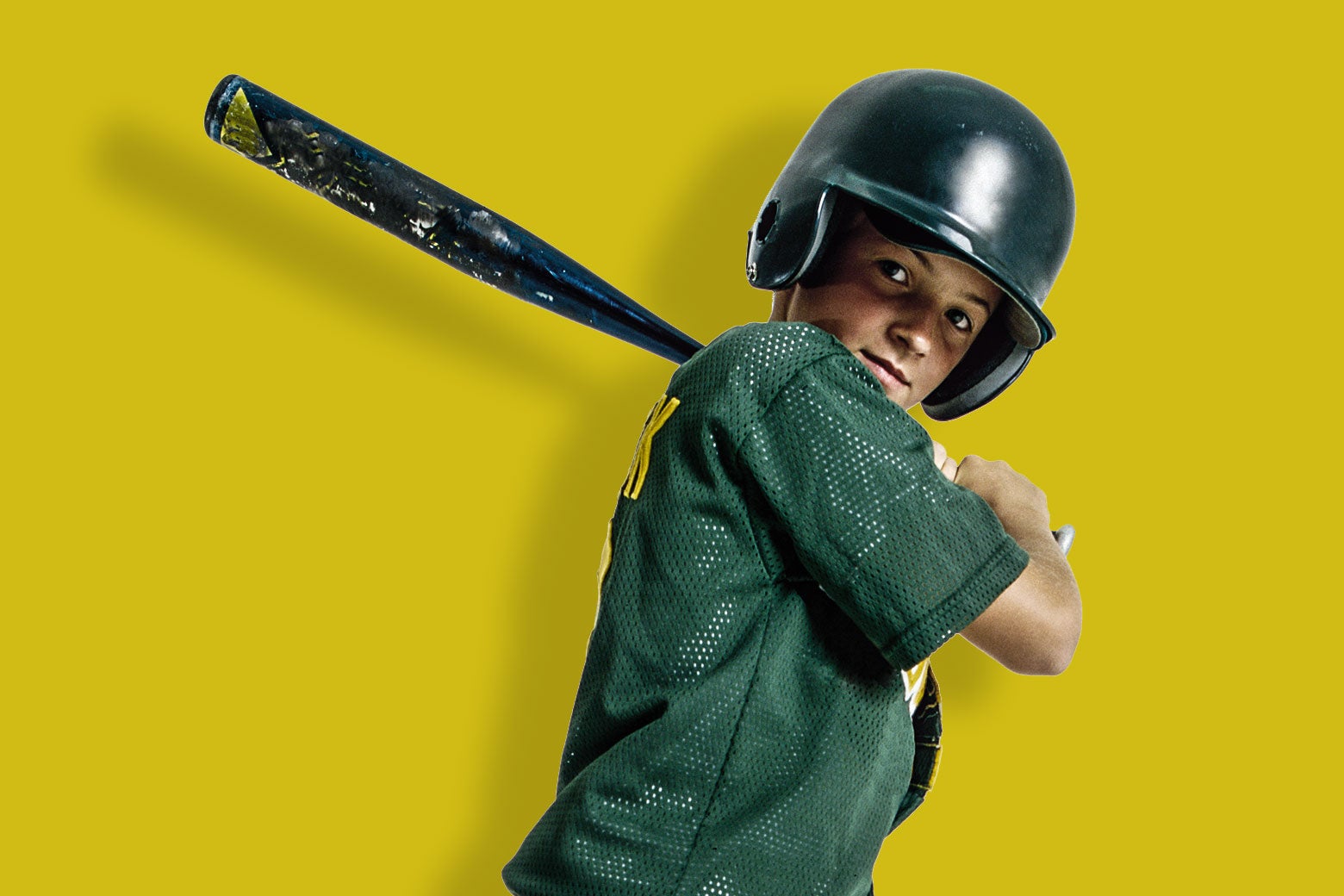 A boy in a green baseball jersey stands with bat ready to swing against a bright yellow background. 