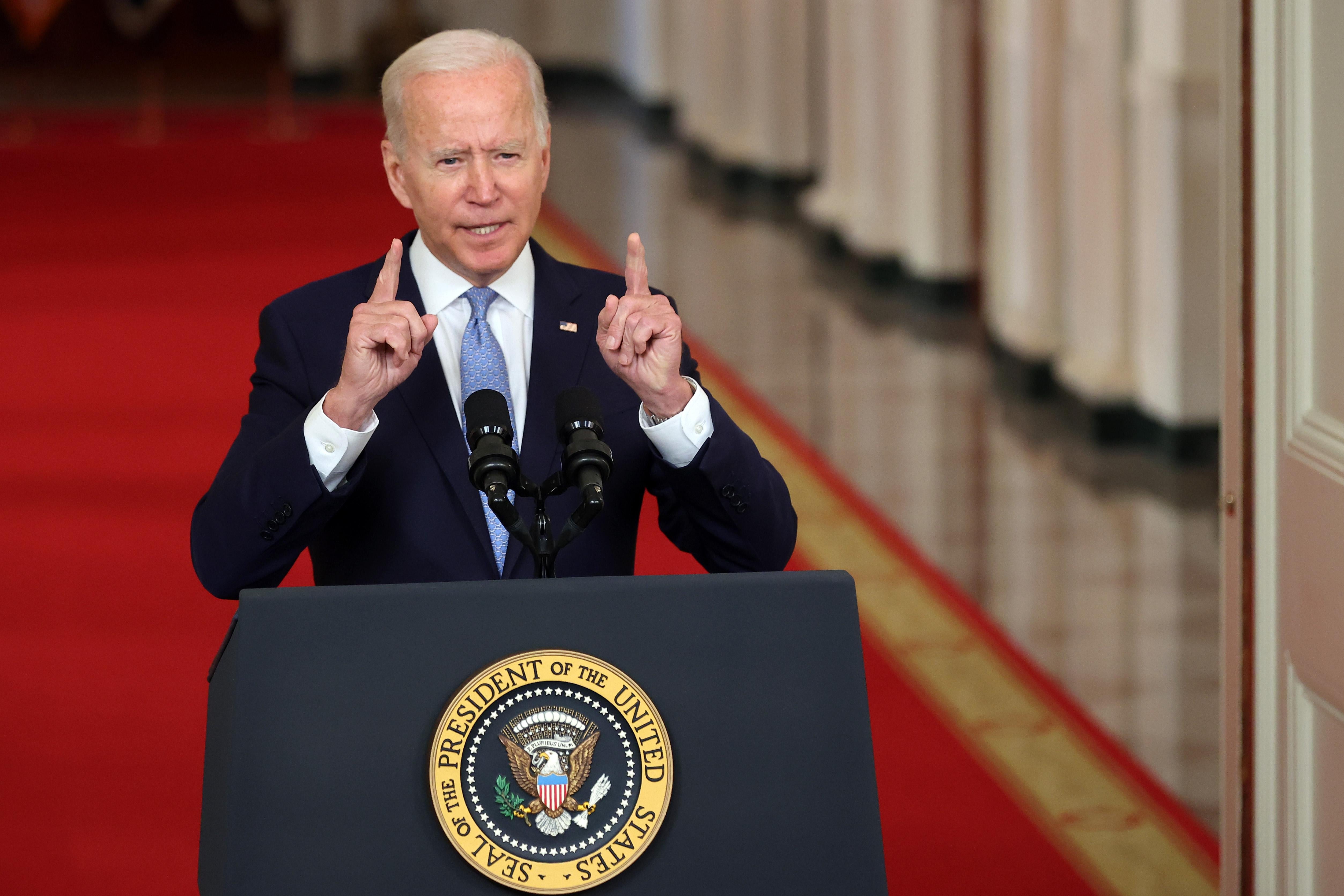 Biden standing behind a mic, pointing up