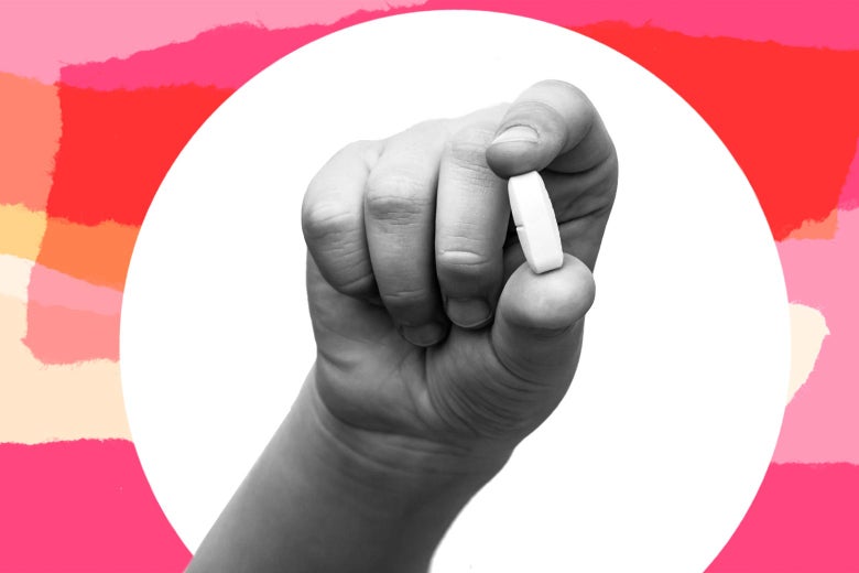 Child's hand holding a white pill.