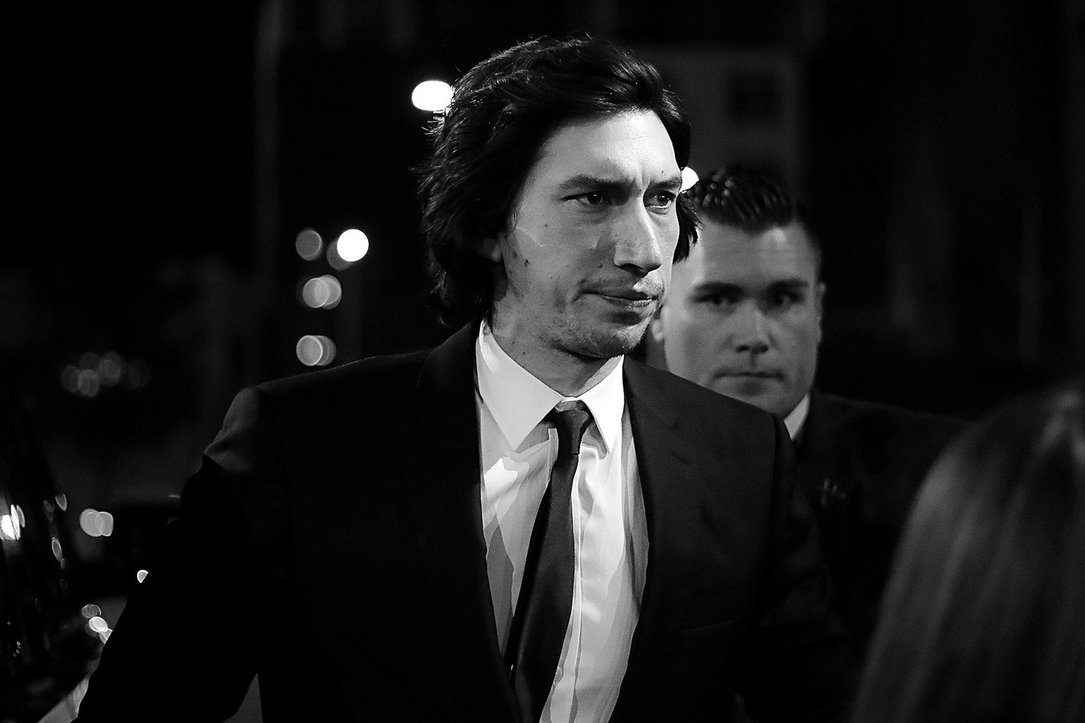 In black and white, Adam Driver wears a nice suit.