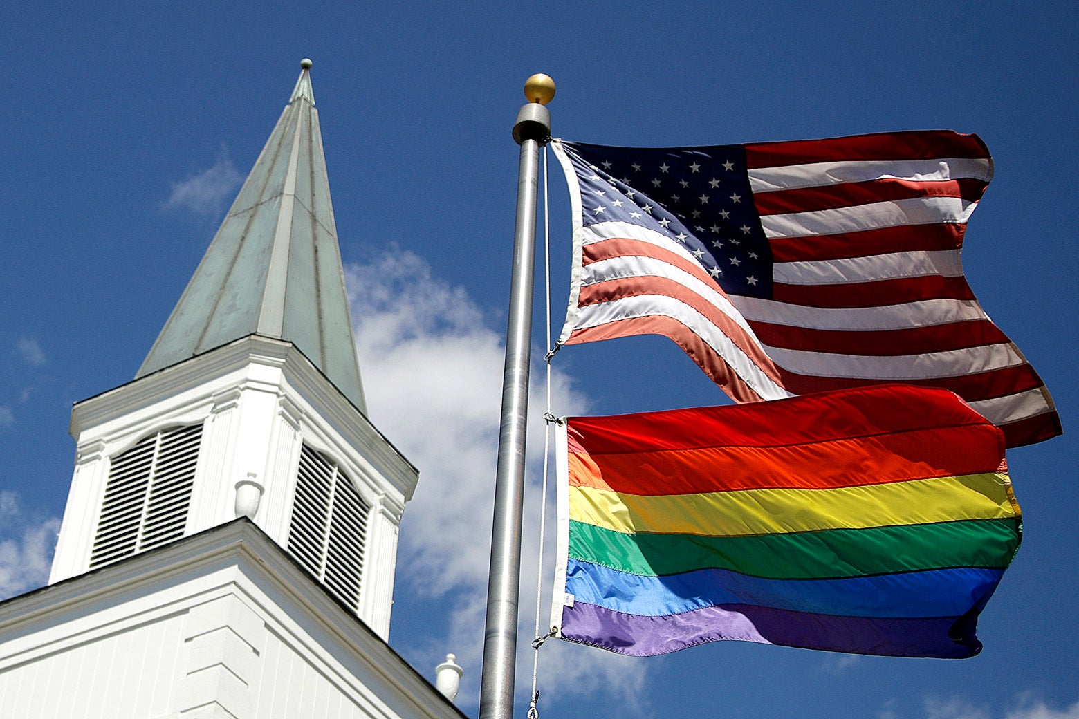 A rainbow flag flies along with the U.S. flag in front of a Methodist church.