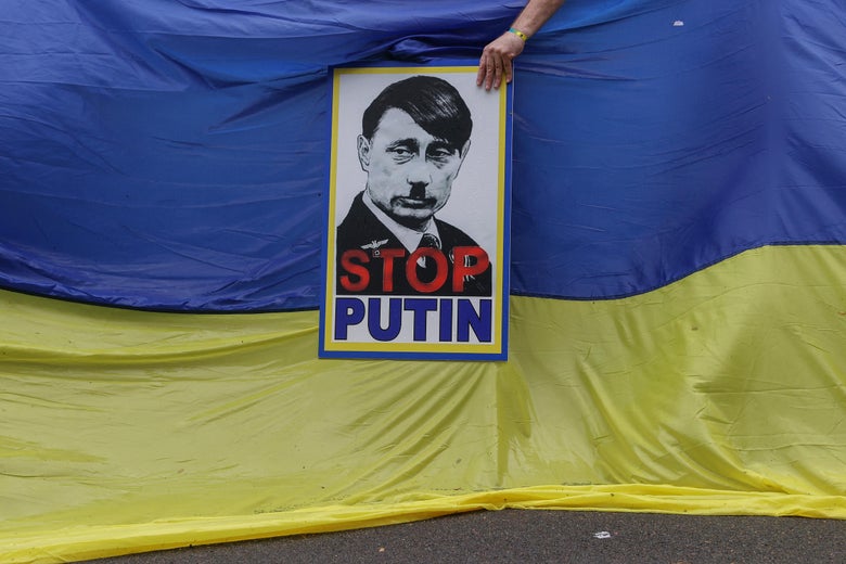 A member of South Africa's Ukrainian Association holds a poster depicting Russian President Vladimir Putin as Adolf Hitler during a protest in support of Ukraine in front of the Russian Embassy in Pretoria, on February 25, 2022. 