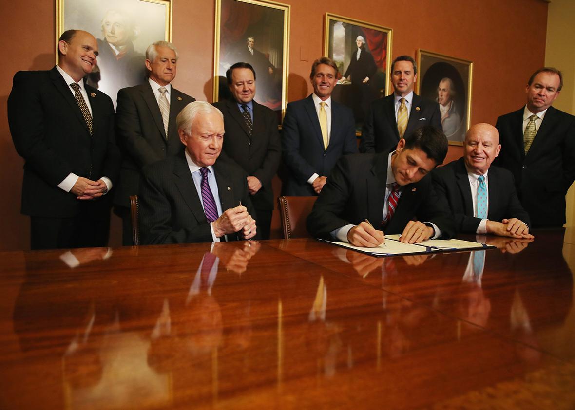 House Speaker Paul Ryan, signs the American Manufacturing Competitiveness Act of 2016, while flanked by Ways and means Committee Chairman Kevin Brady (R-TX), (R), and Senate Finance Committee Chairman Orrin Hatch (R-UT), (L), along with other members of Congress, on Capitol Hill May18, 2016 in Washington, DC.
