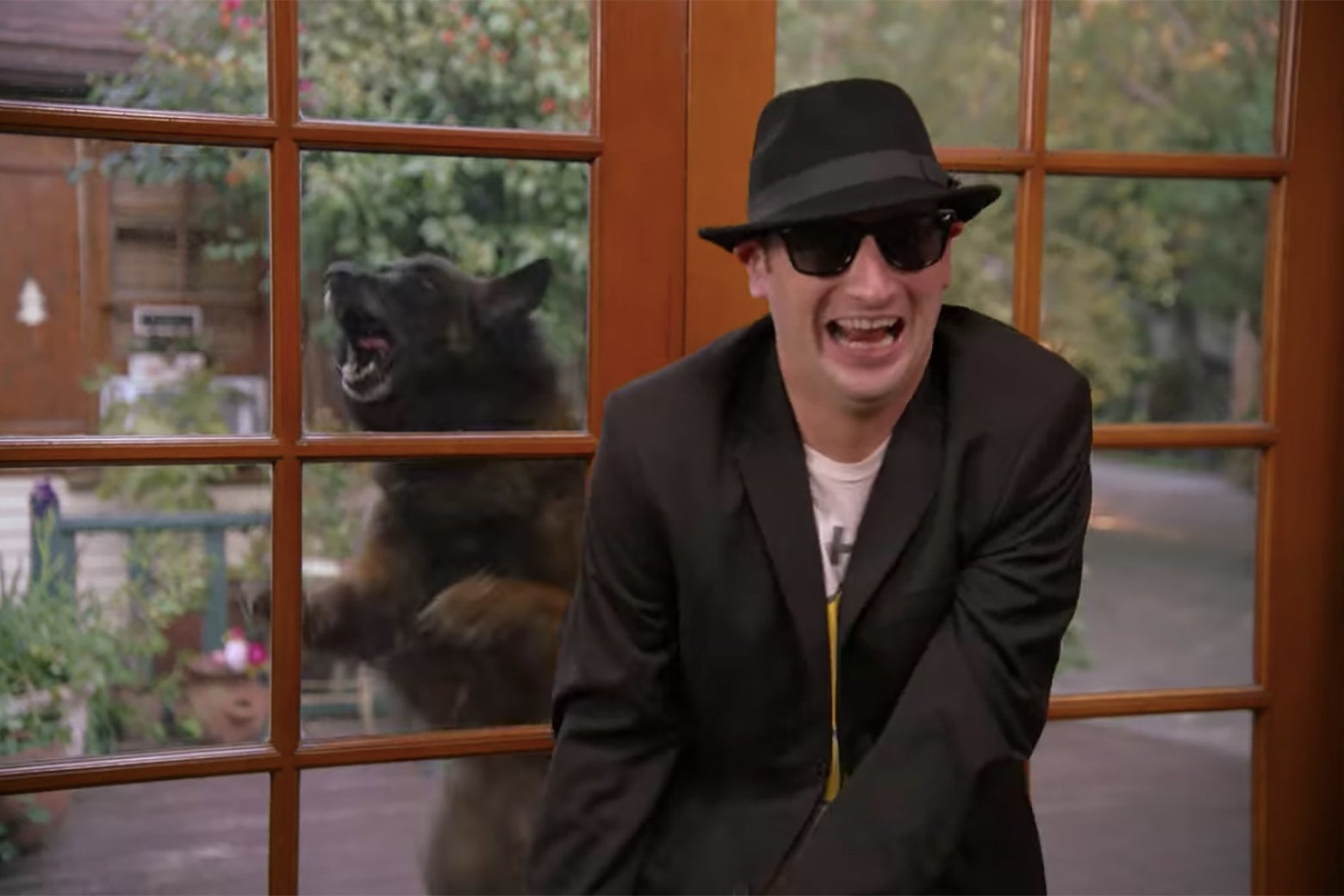 A man in a black suit and sunglasses, with a growling bear behind him.
