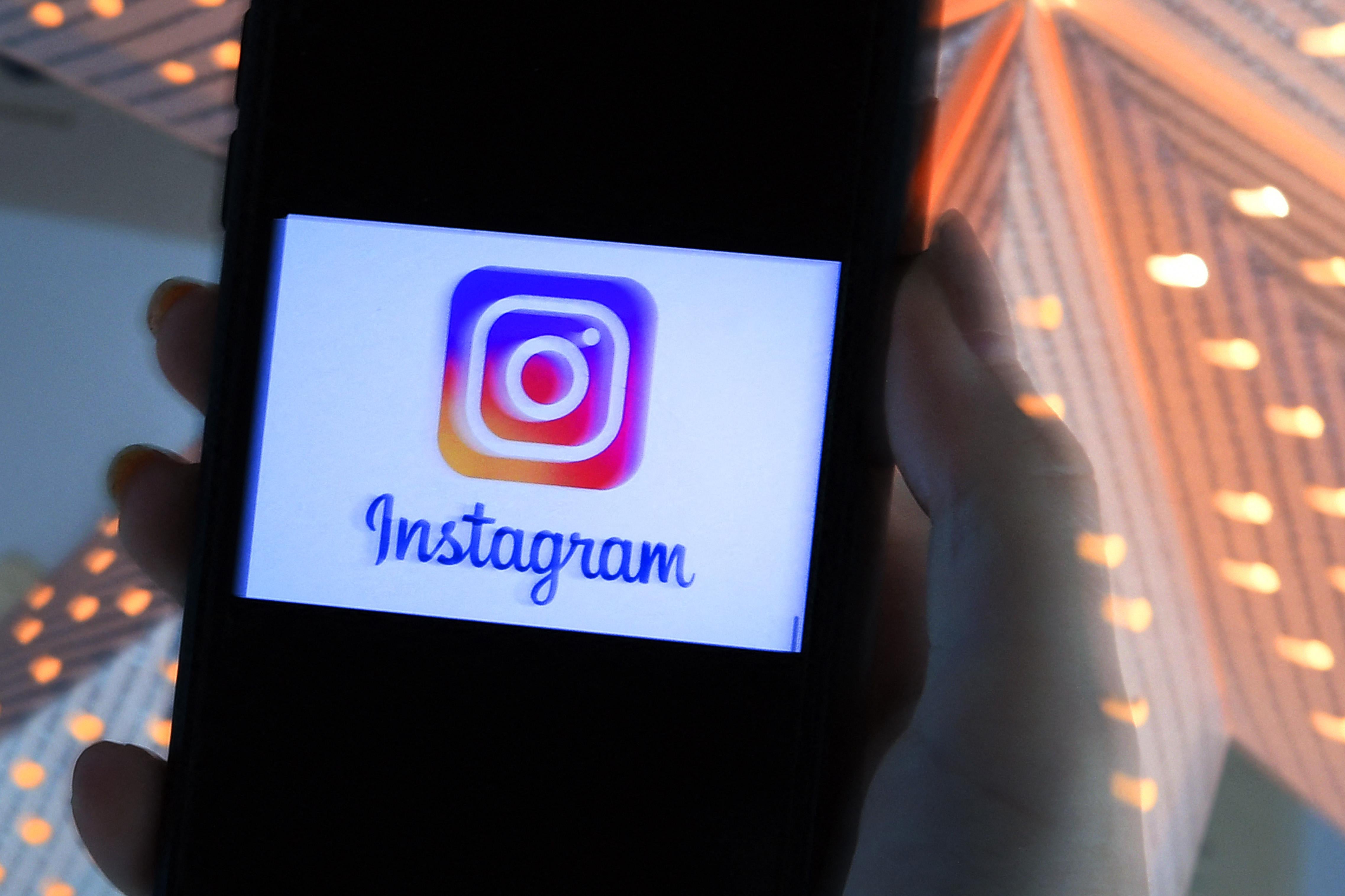 In this photo illustration, a person looks at a smart phone with a Instagram logo displayed on the screen