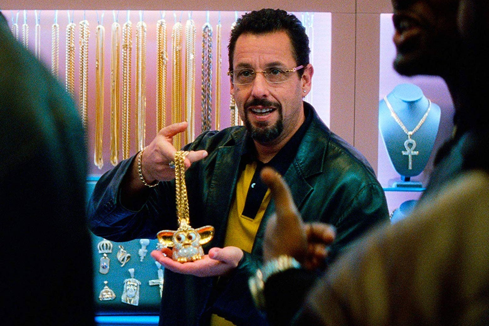 Adam Sandler's Howard holds up a very blinged-out Furby made of gold.