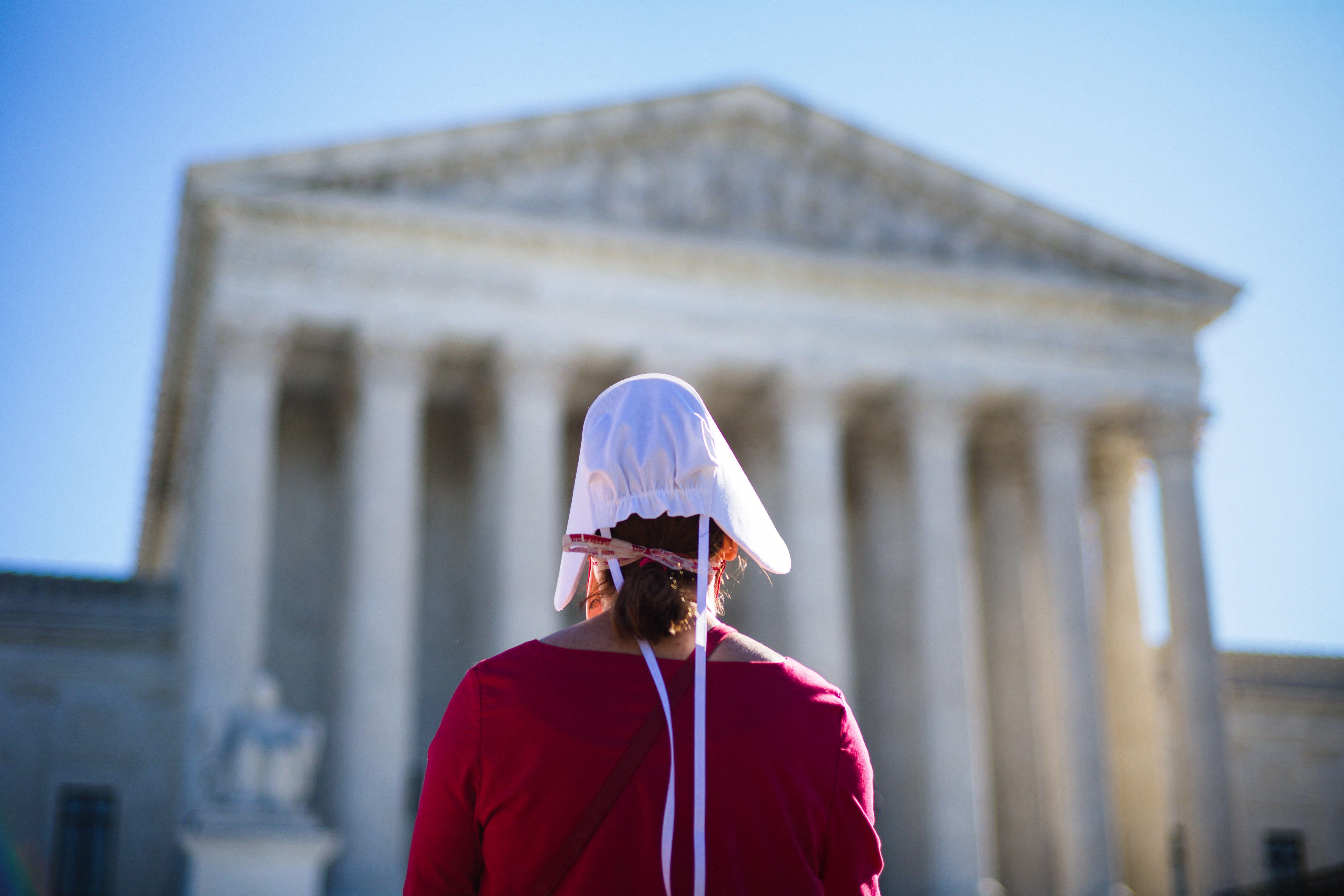 A pro-choice demonstrator dressed in Handmaid's Tale garb standing in front of the Supreme Court. 