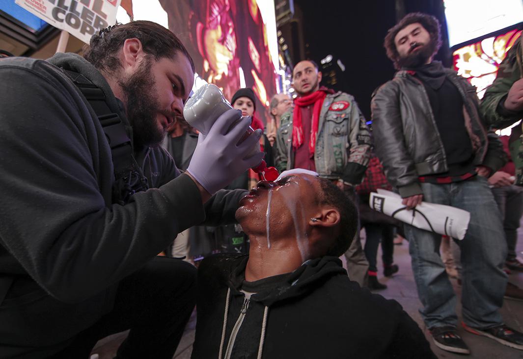 A man helps a protester who was pepper-sprayed as the protesters block Fifth Avenue during protests in New York City on Nov. 25, 2014