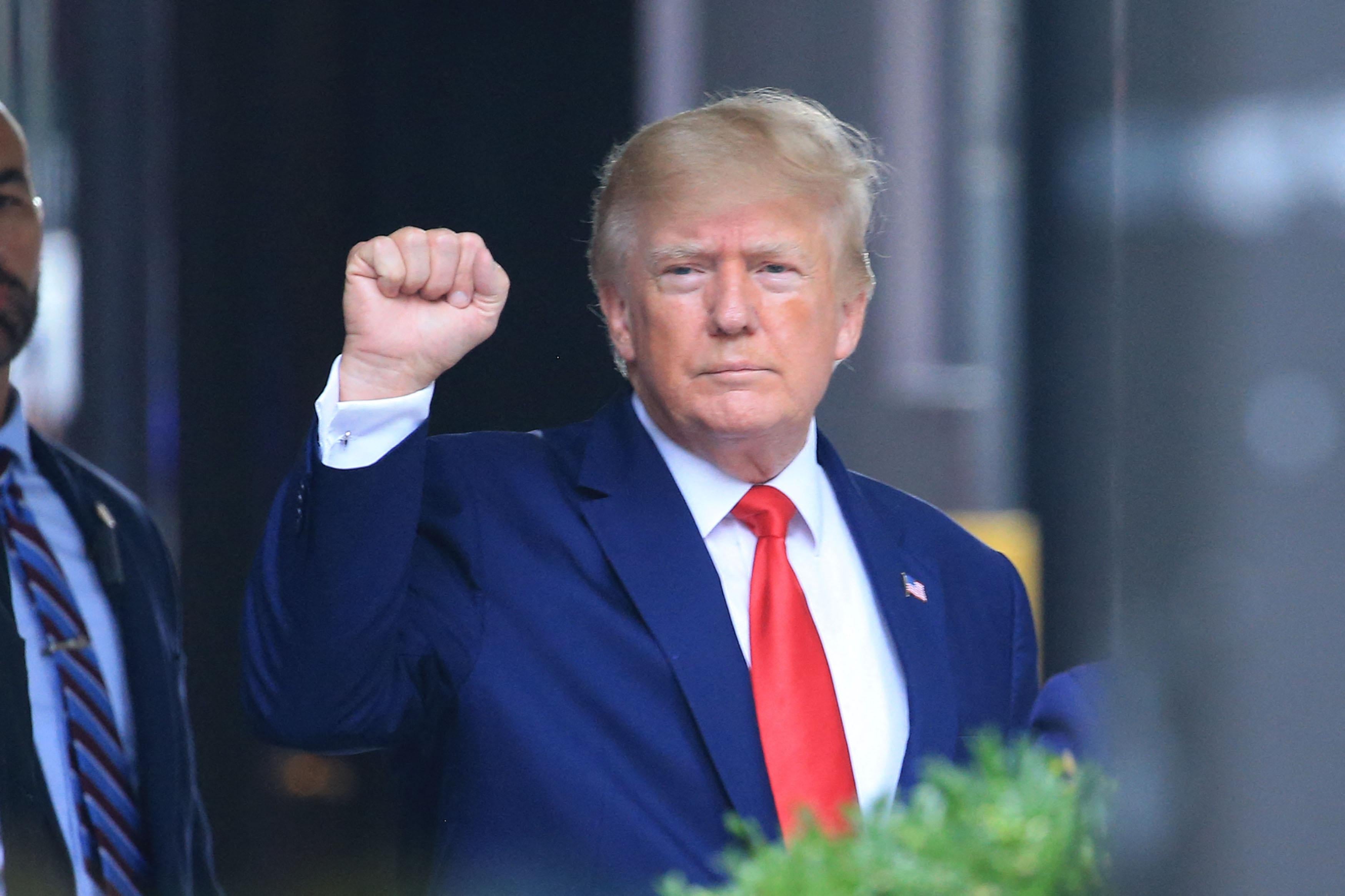 Trump with a frown raises his fist.