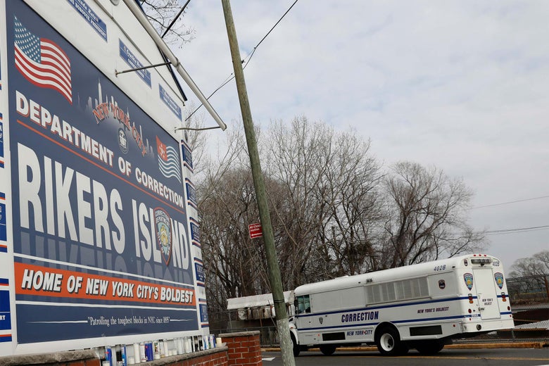 A white bus with the word CORRECTION on it in large letters drives past a Rikers Island sign.