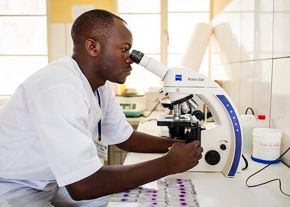 Laboratory assistant working with a microscope at the Ngoma health center on February 5, 2014 in Ngoma, Rwanda.