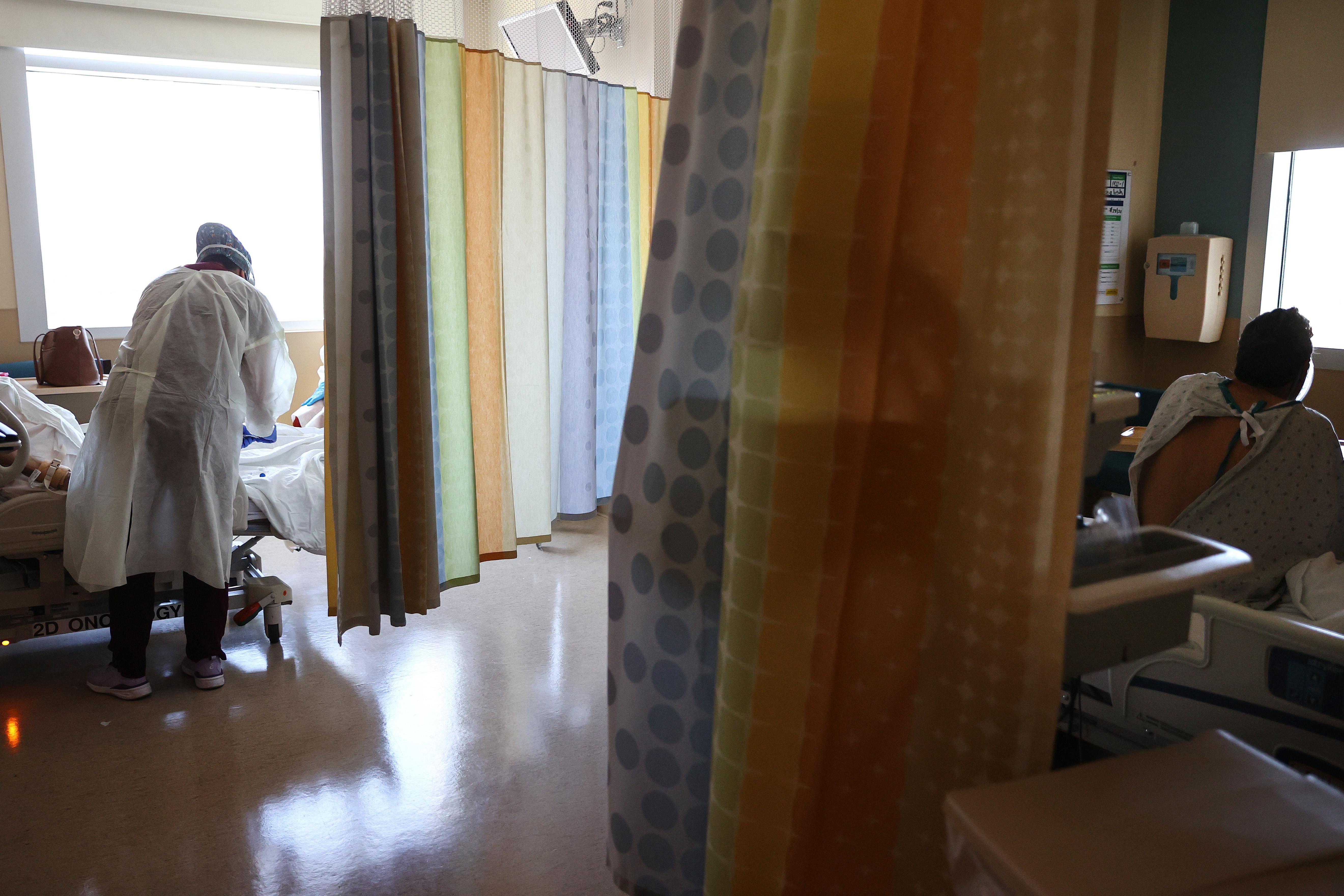 A registered nurse seen from behind caring for a COVID-19 patient as another COVID-19 patient rests in the improvised COVID-19 unit at Providence Holy Cross Medical Center in the Mission Hills neighborhood on July 30, 2021 in Los Angeles, California. 