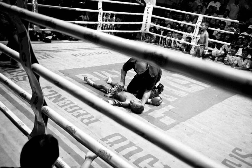 Bank has lost the boxing match against Tountong and is lying unconscious on the ground.