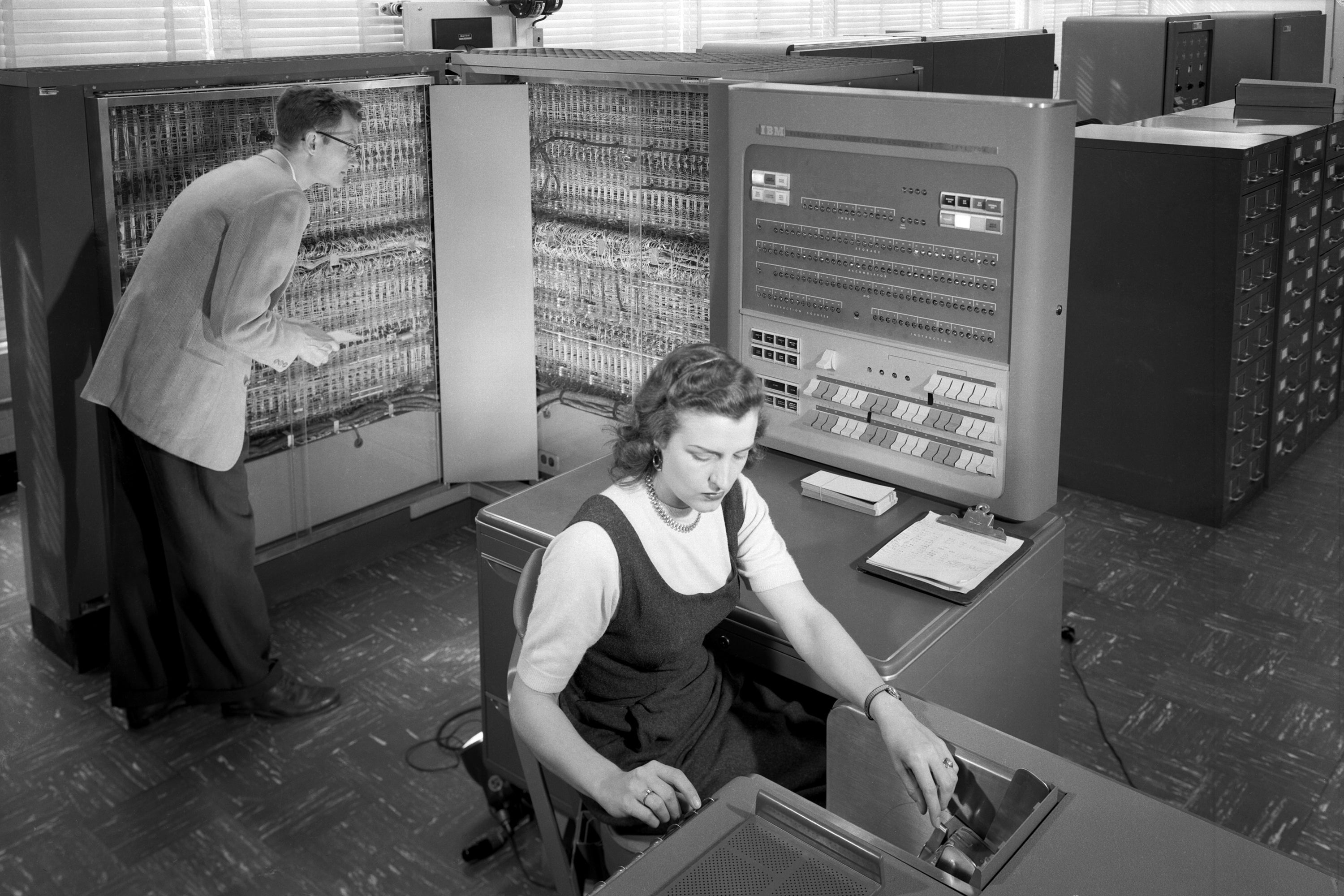 A man and woman work with an IBM data processing machine in 1957.
