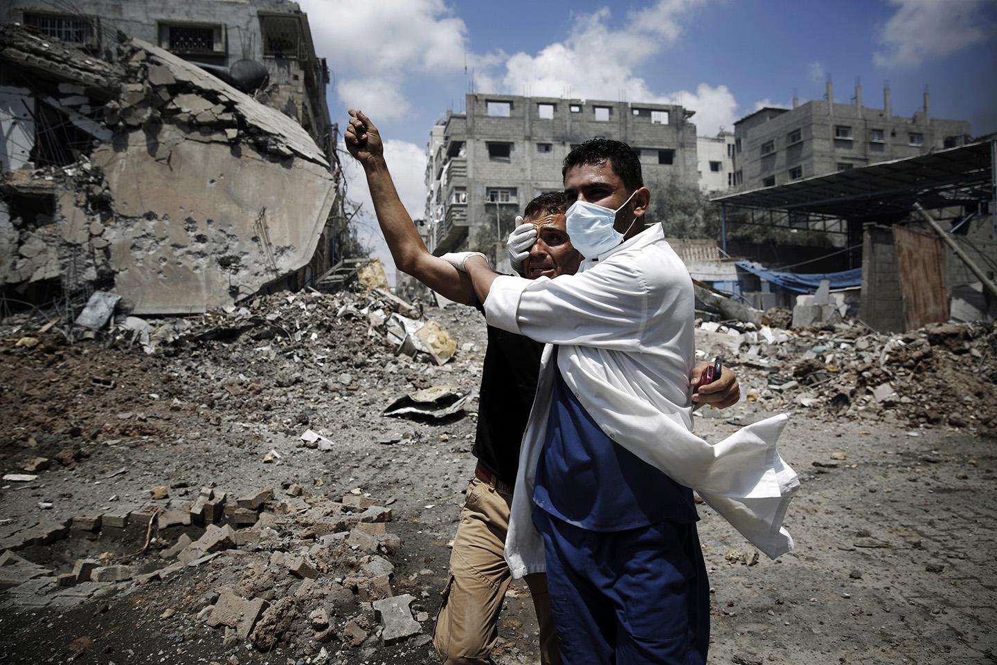 A medic helps a Palestinian in the Shejaia neighborhood, which was heavily shelled by Israel during fighting, in Gaza City.
