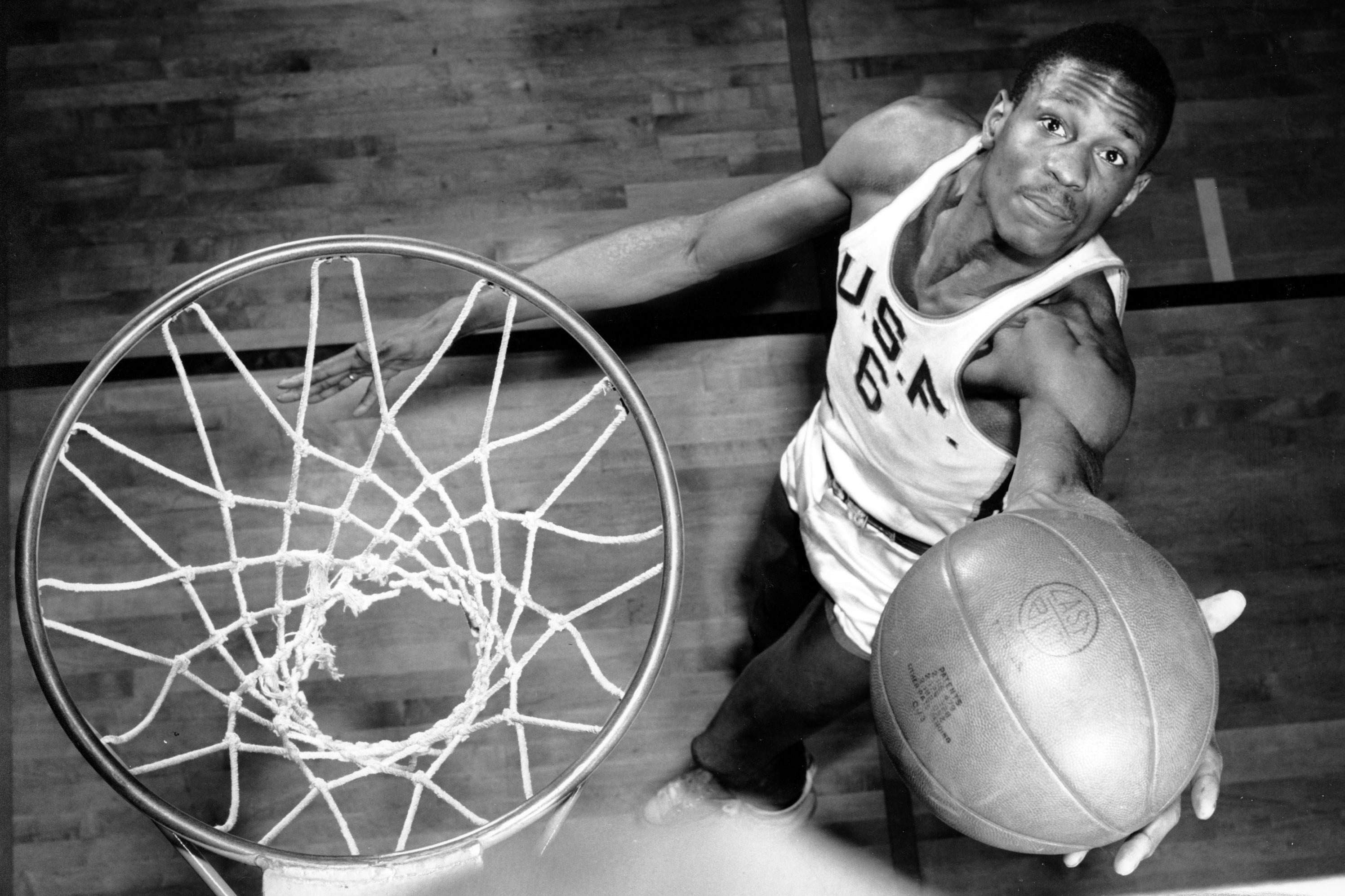 An overhead shot shows a very skinny, very young, goatee-less Bill Russell rising to the basket, a hopeful look in his eyes
