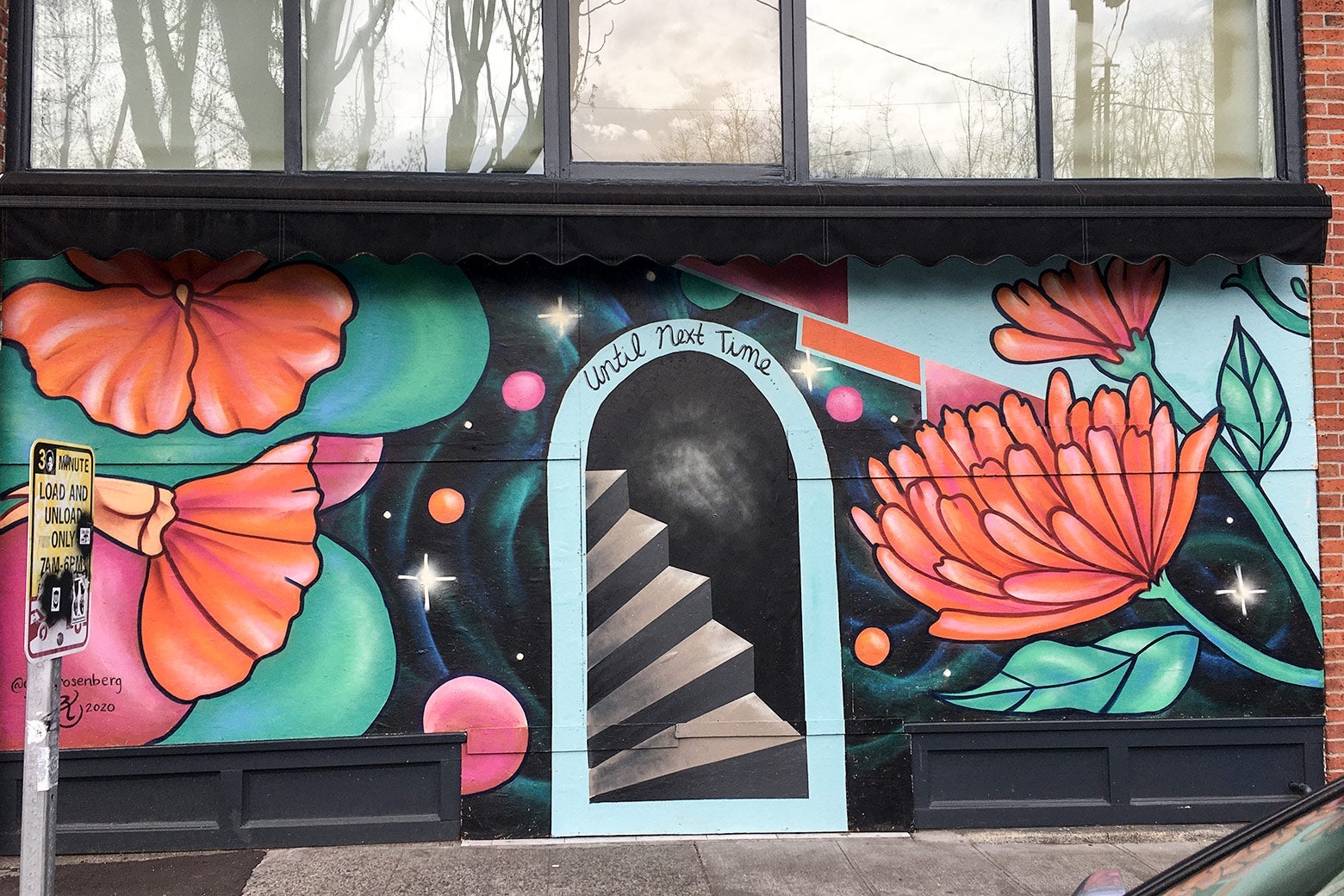 A mural of big red-orange flowers surrounding a faux door and stairs.