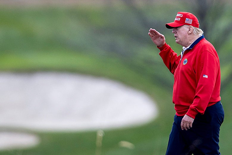 Trump in a red MAGA cap saluting as he walks through a golf course, with green and bunkers visible in the background.