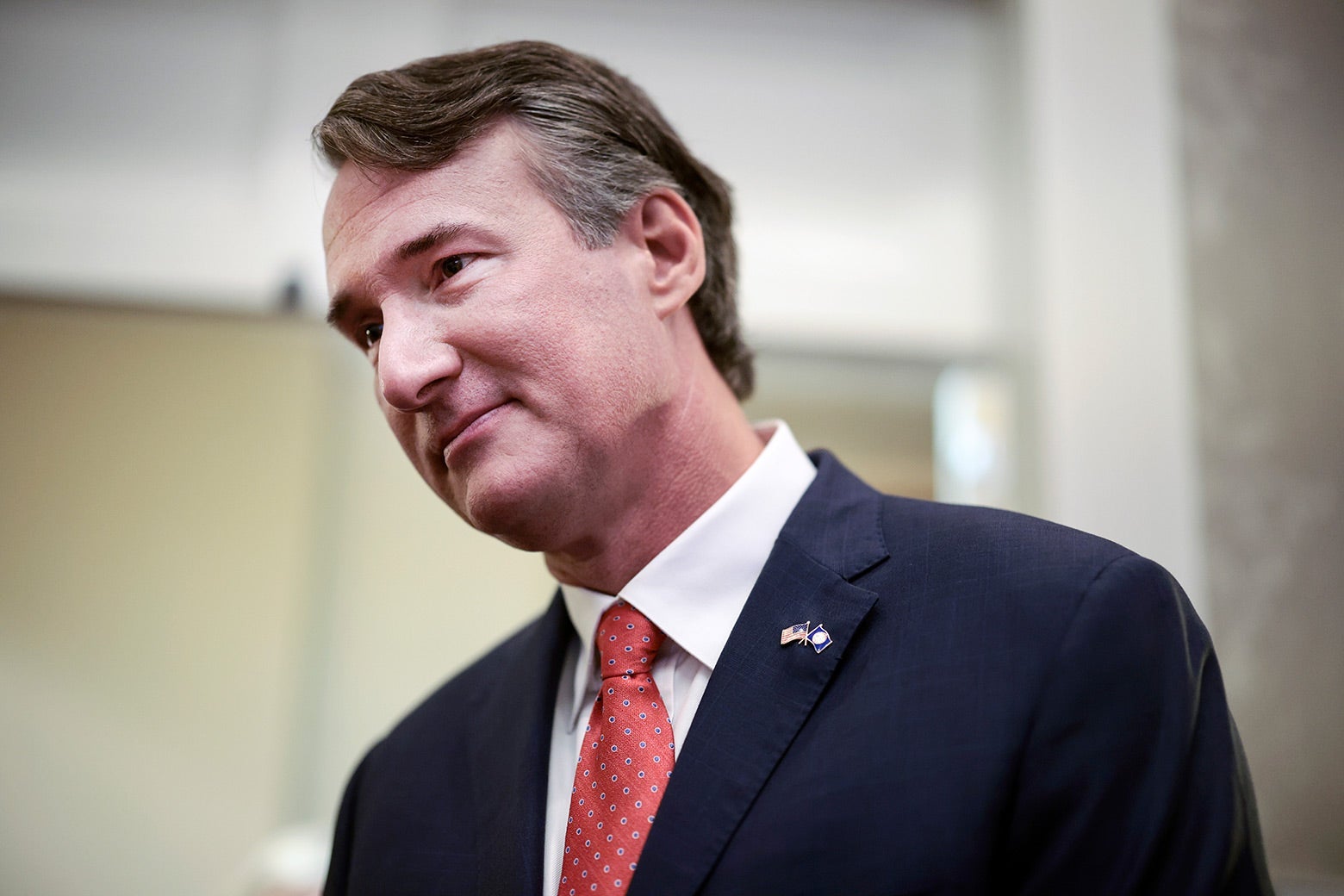 A white man in a suit with a red tie.