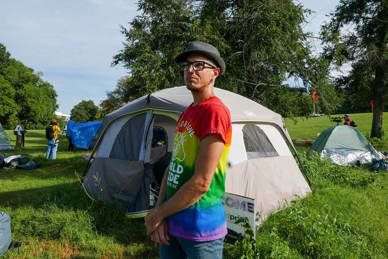 Jesse Wall, wearing a colorful t-shirt, at his tent.