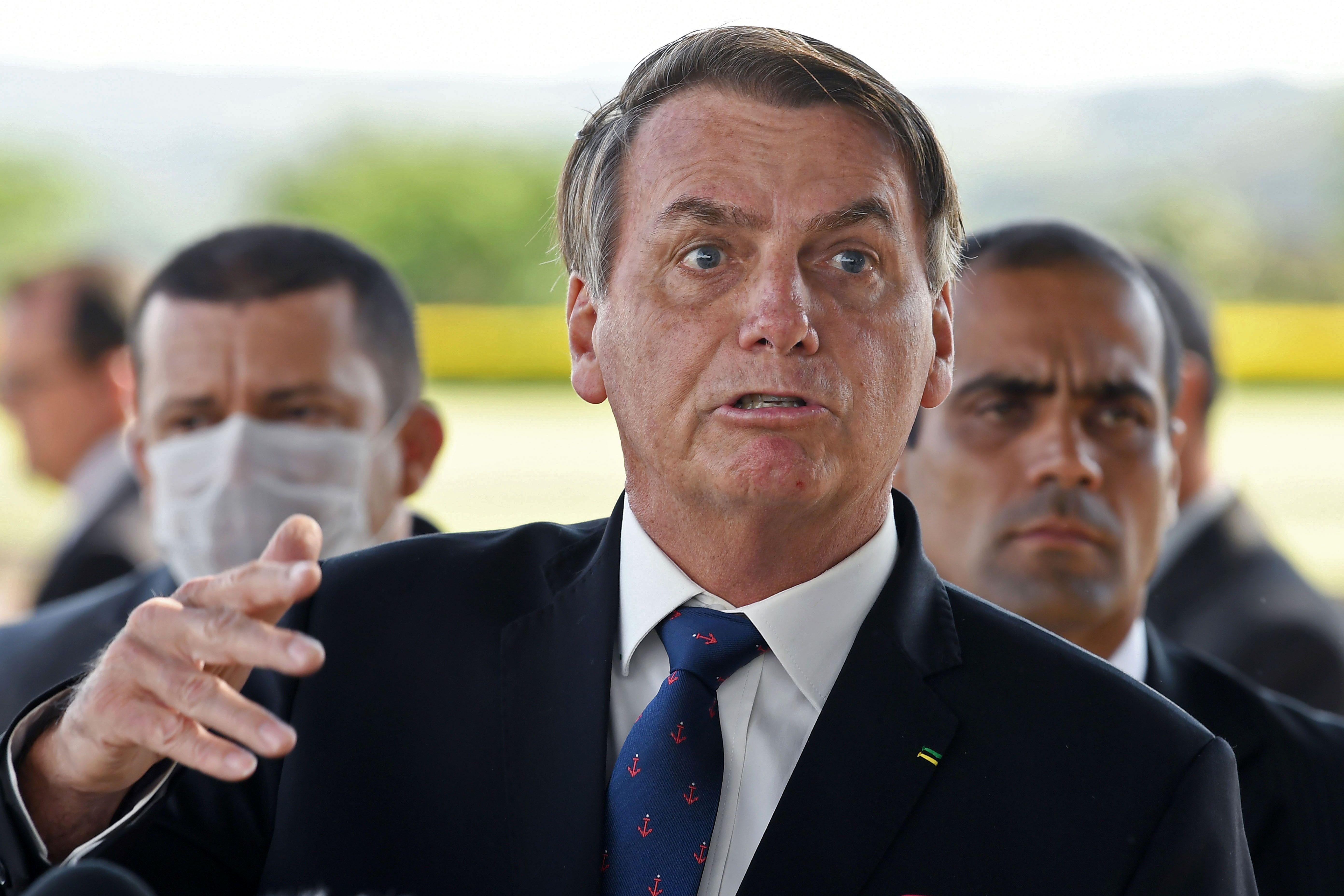 Bolsonaro speaks. An aide behind him wears a surgical mask.