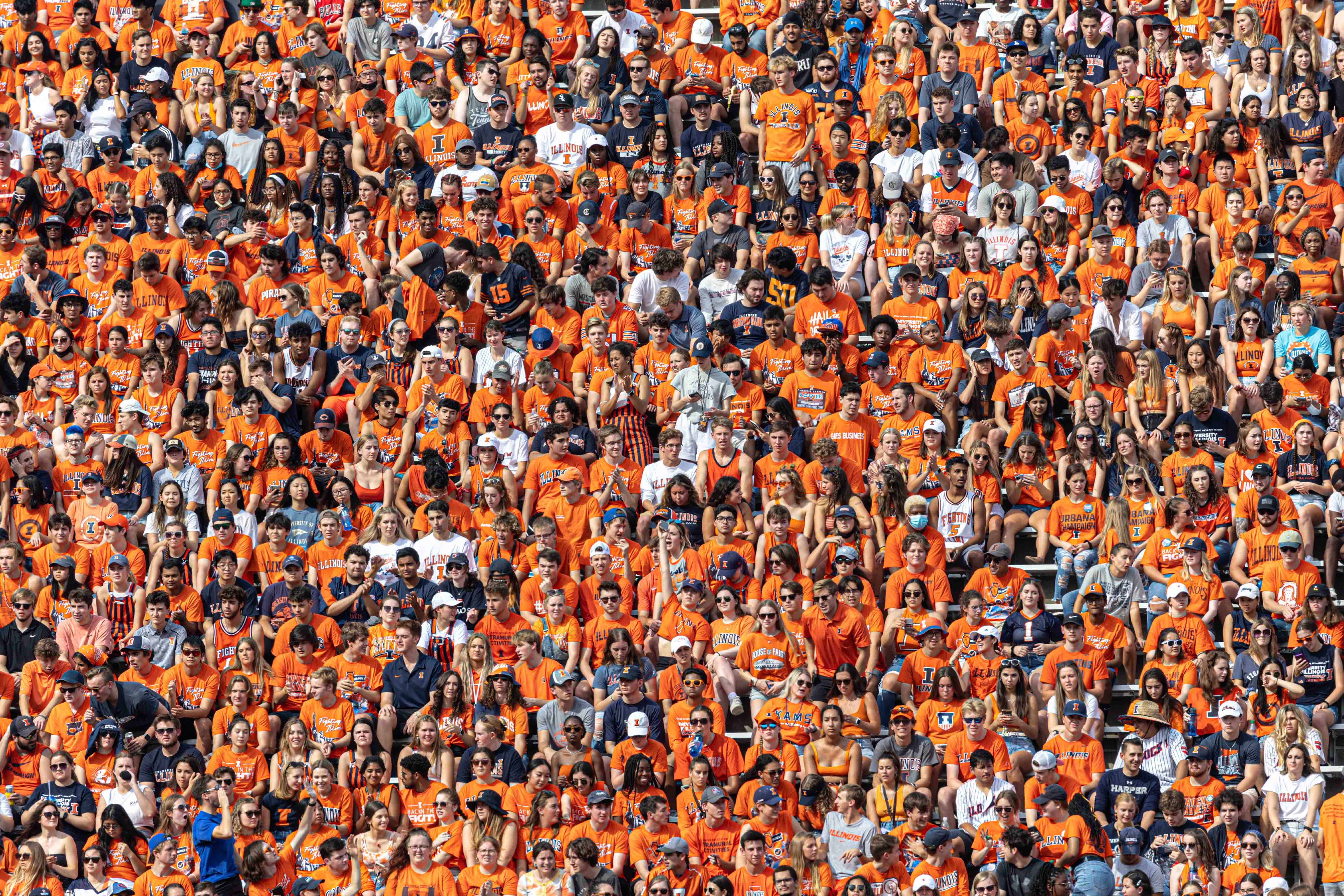 A stadium bleacher full of people wearing orange shirts.