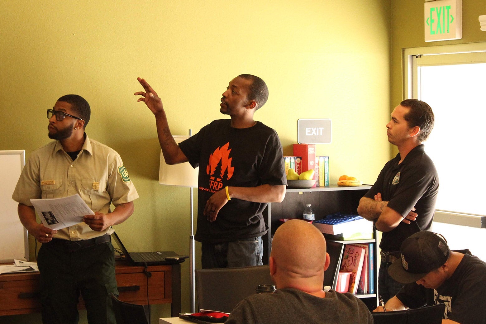 Three men lead a training at the front of a classroom