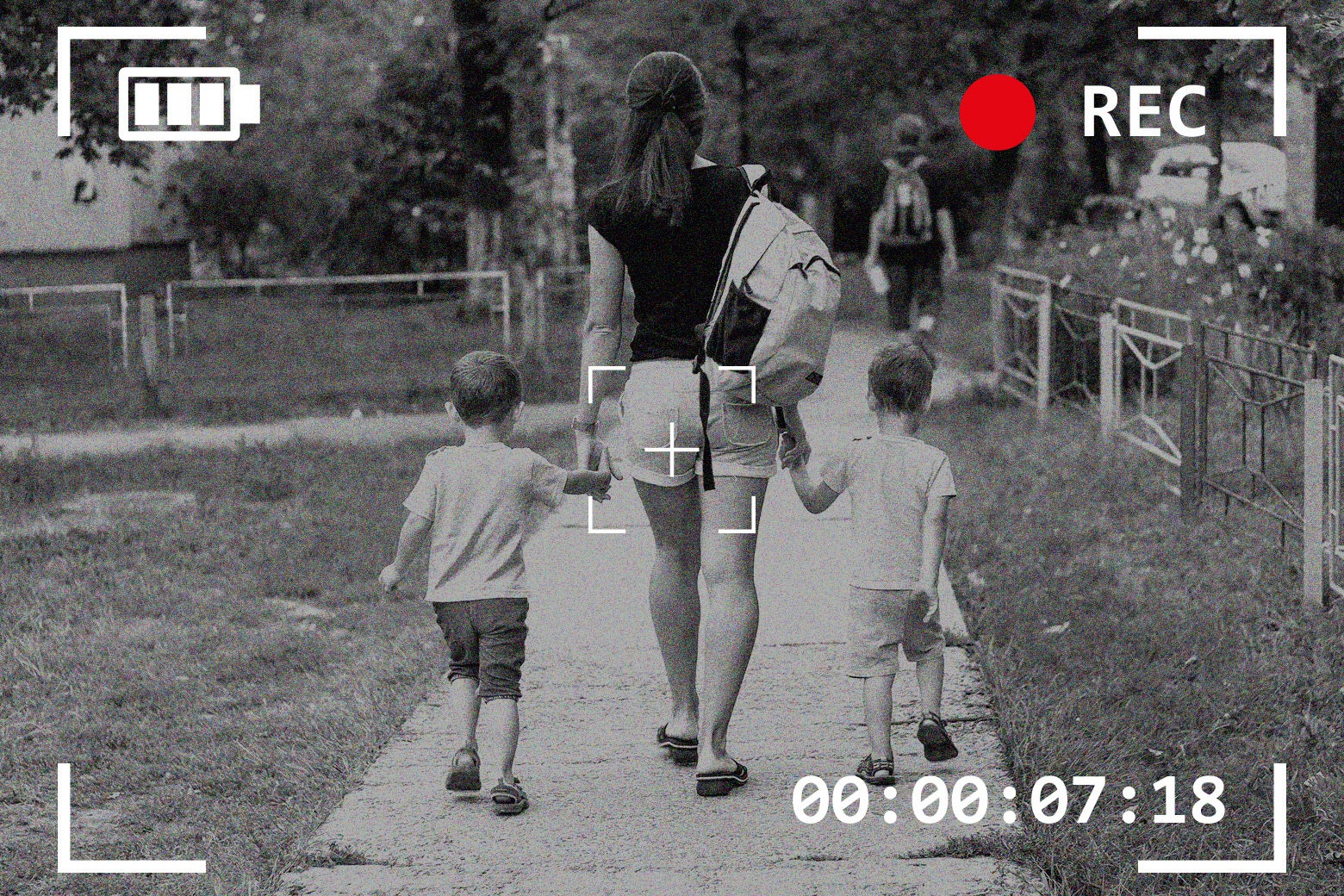 A nanny walking two boys to school through the viewfinder of a hidden camera.