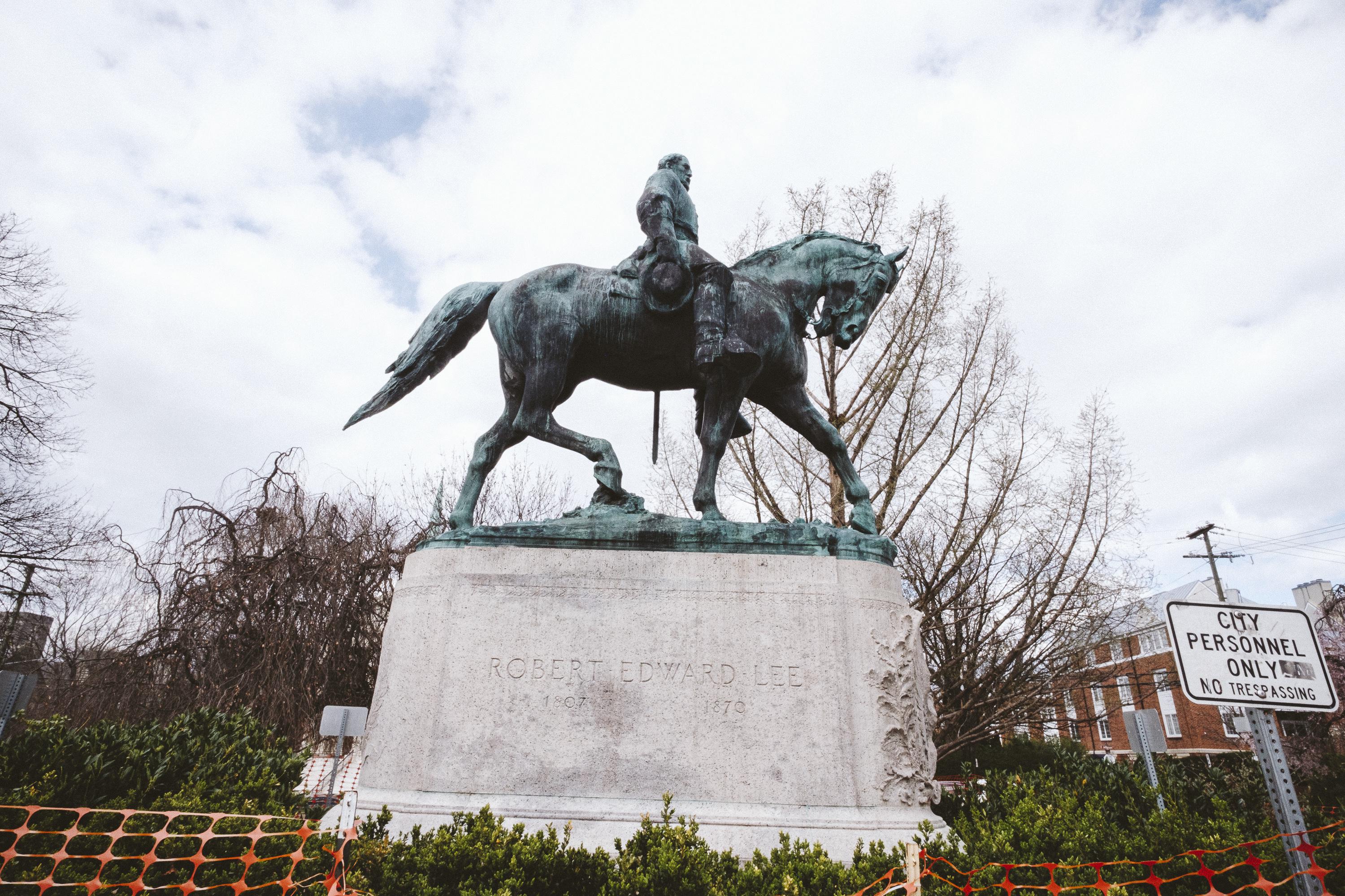 Statue of Lee on a horse with plastic fencing around it on a cloudy day