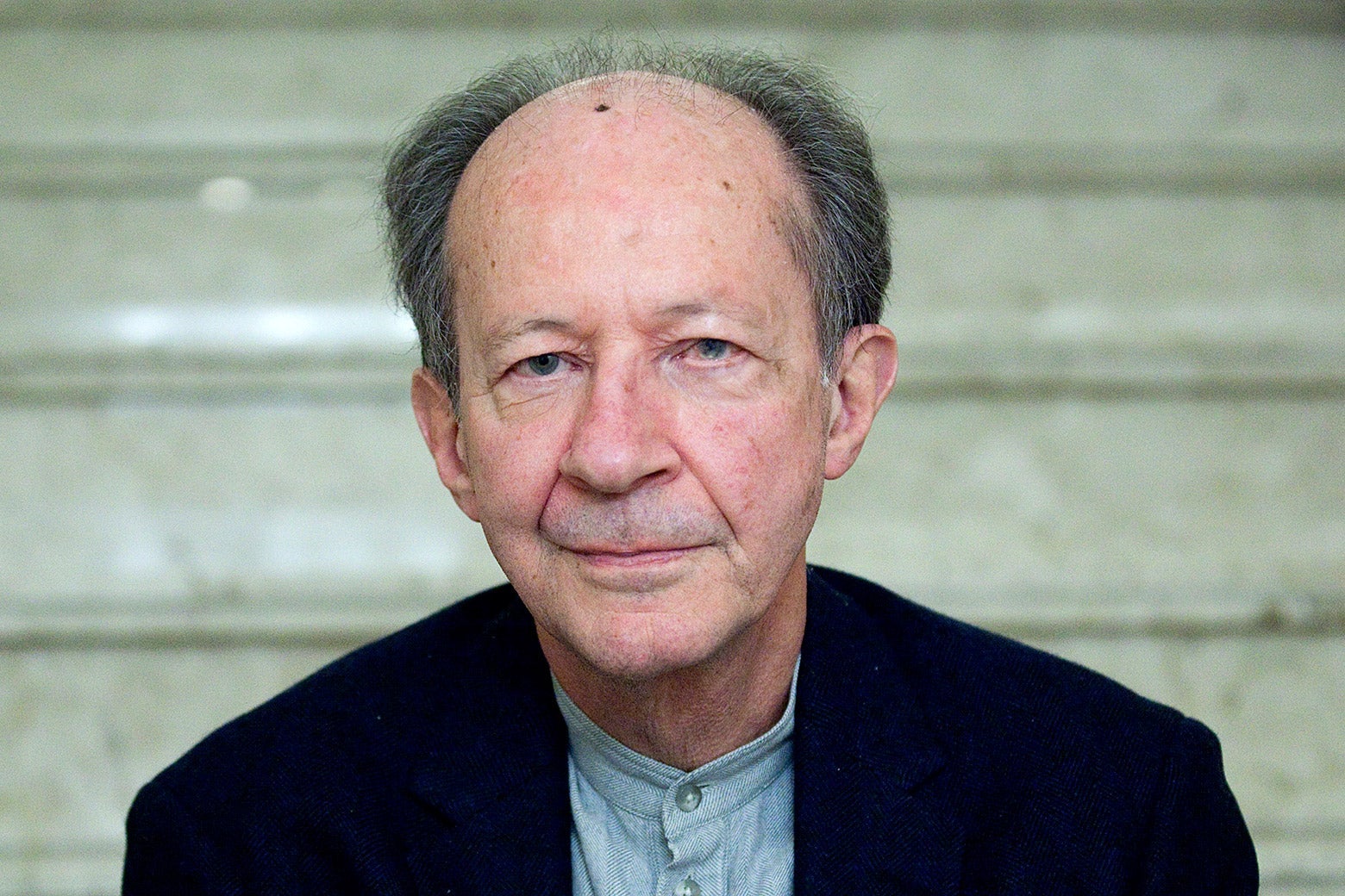 A man slightly smiling in front of marble steps
