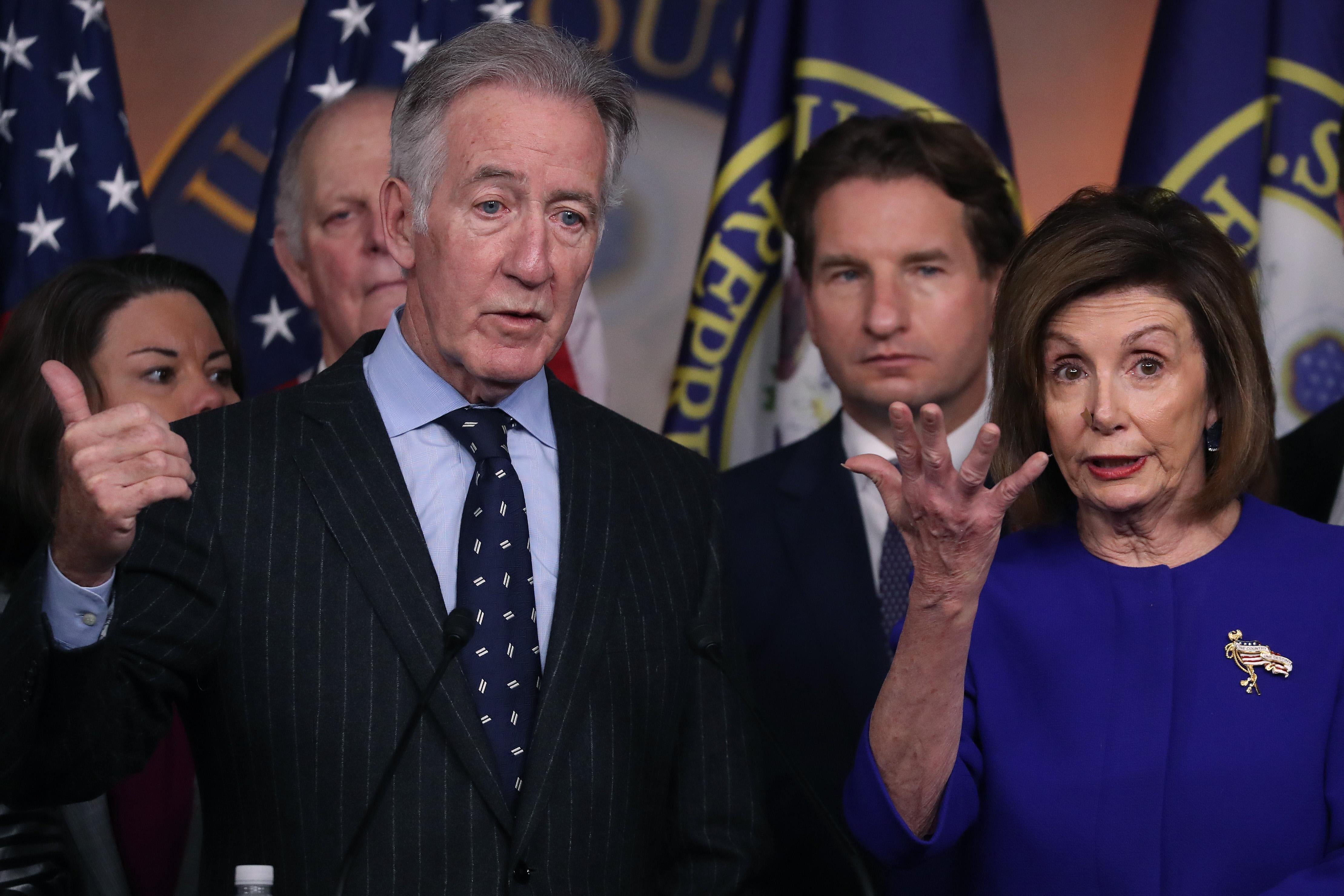 Richard Neal gestures from behind a podium with Nancy Pelosi and other House Democrats beside him.