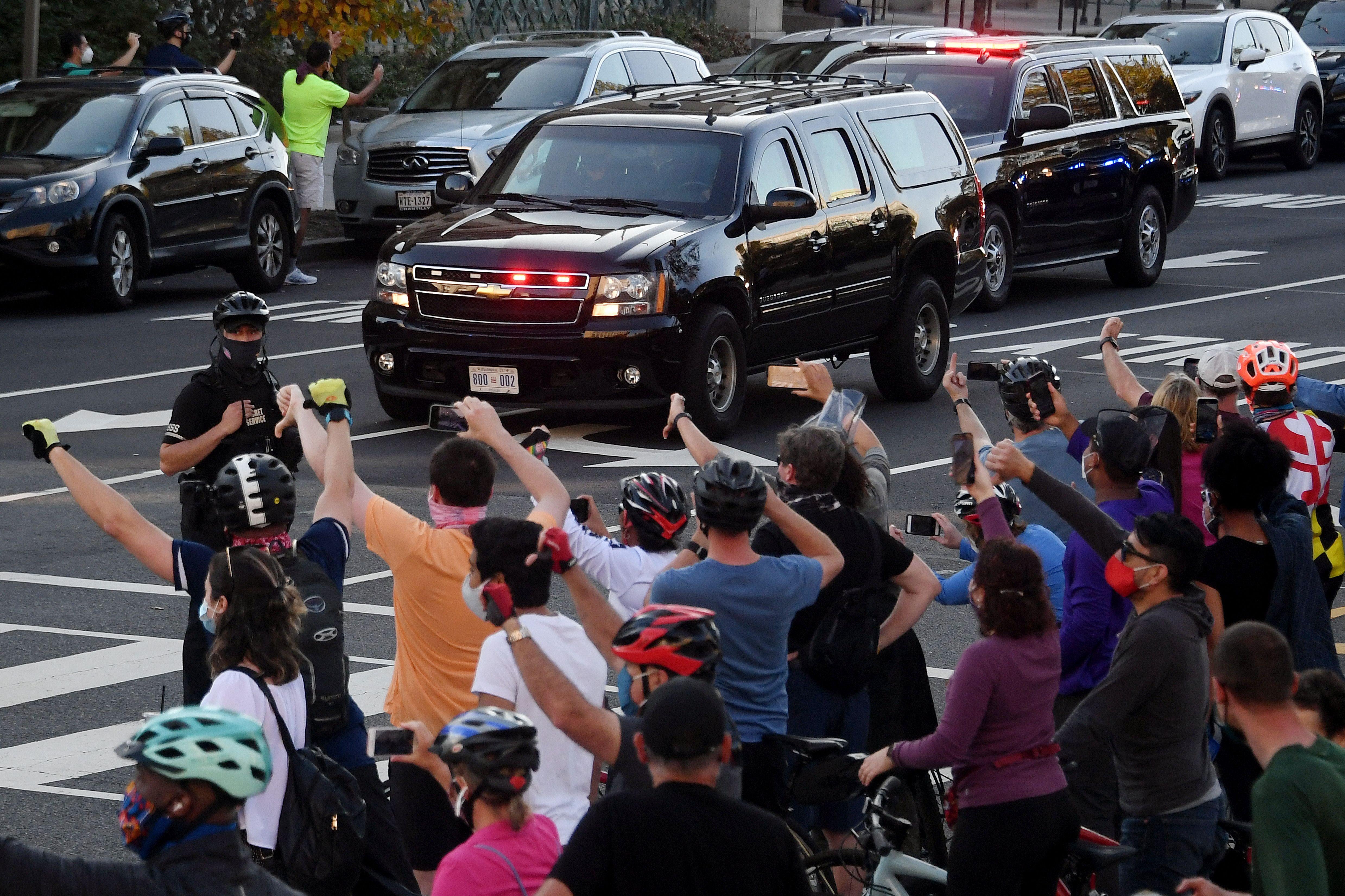People react as the motorcade carrying President Donald Trump returns to the White House on November 7, 2020 in Washington, D.C.