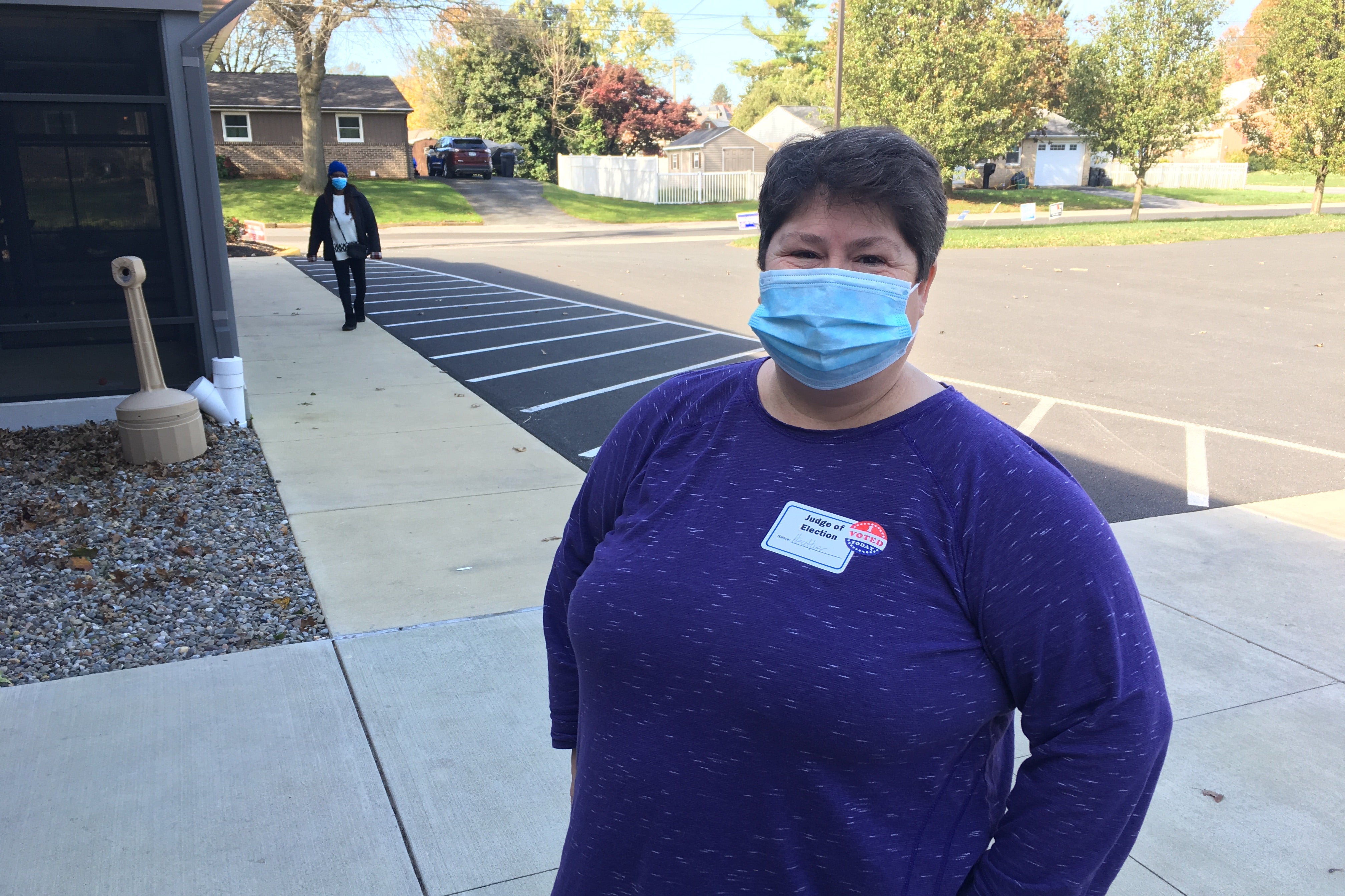 Woman wearing a mask smizes while standing outside on a sidewalk