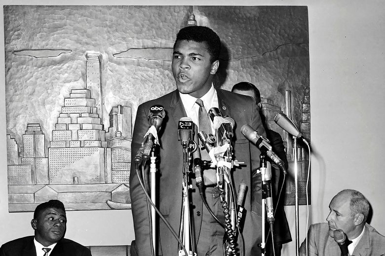 Muhammad Ali speaks standing at a cluster of microphones