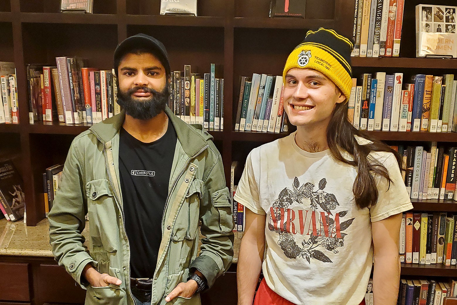The two organizers stand in front of shelves full of books at the library.