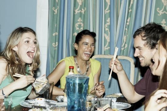 People laugh around a dinner table.