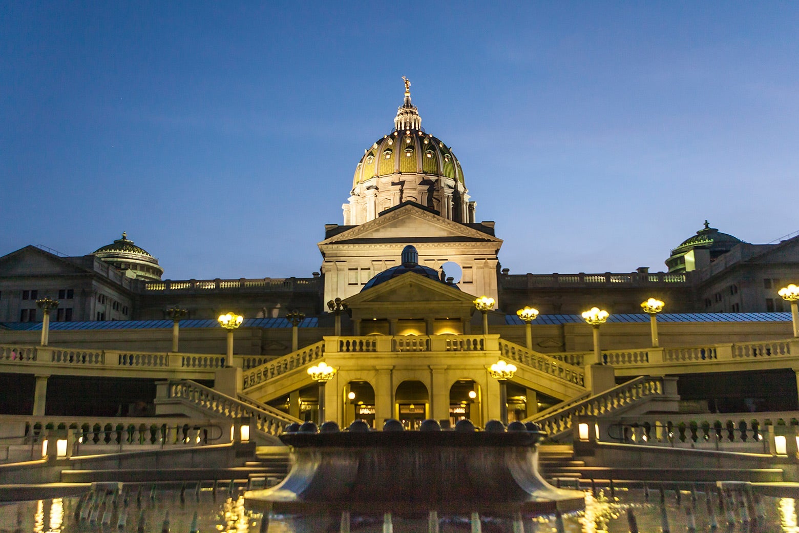The ornate Capitol lit by yellow lamplight at dusk.