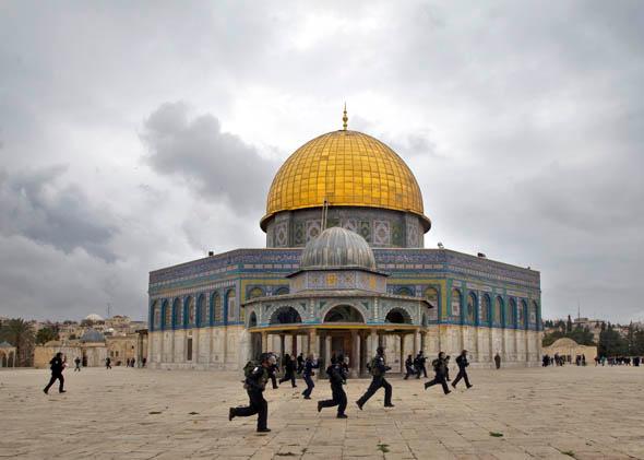 Israeli riot police chase Palestinian stone-throwers (unseen) past the Dome of the Rock mosque following Friday prayers at Jerusalem's al-Aqsa mosque compound, on December 6, 2013. 