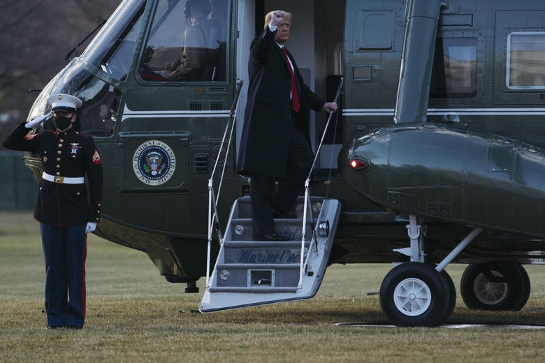 Donald Trump raises his fist to an audience off-screen as he stands on the stairs to Marine One. A masked Marine stands next to the helicopter, saluting.