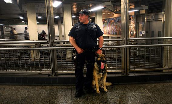 A police officer and his dog, Buster, watch pedestrians in the subway station.