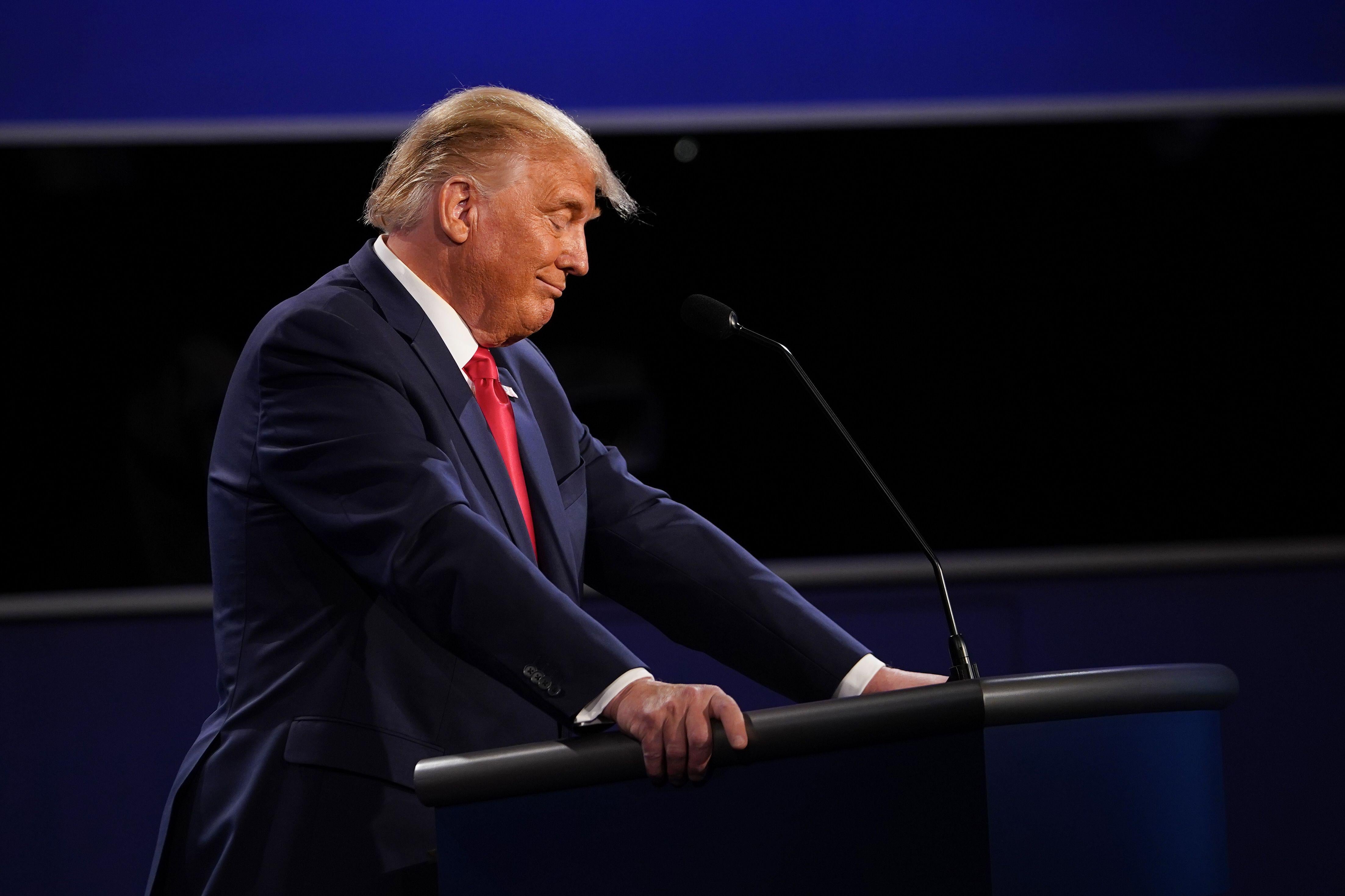 Trump smirks as he stands at his lectern on the debate stage