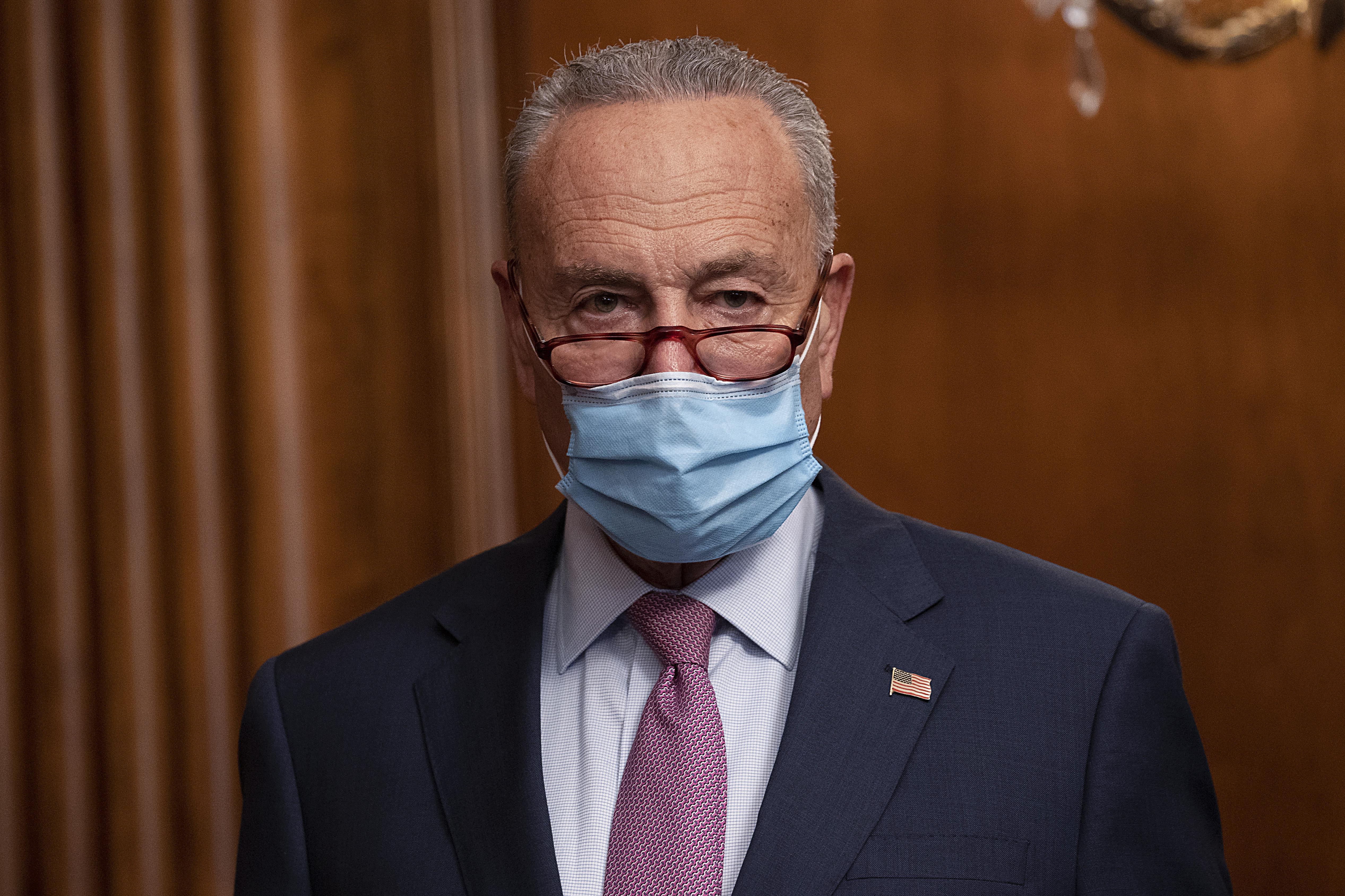 Chuck Schumer standing, wearing a mask, looking stern