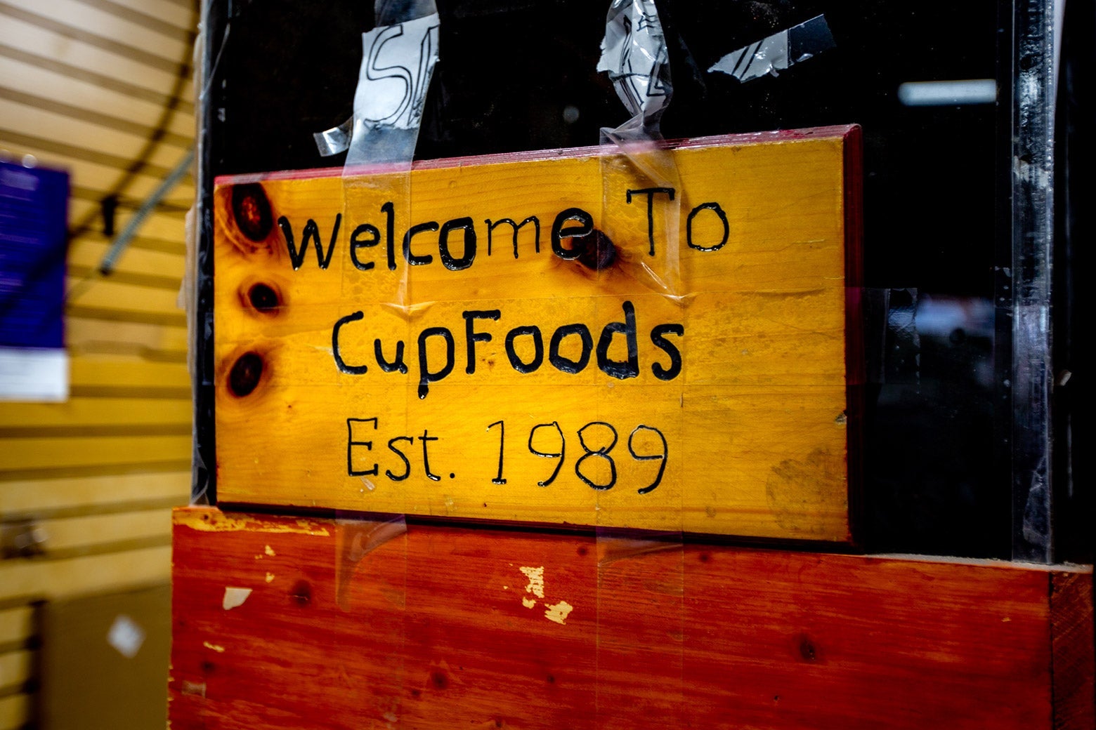 A piece of wood carved to read, "Welcome to CupFoods Est. 1989."