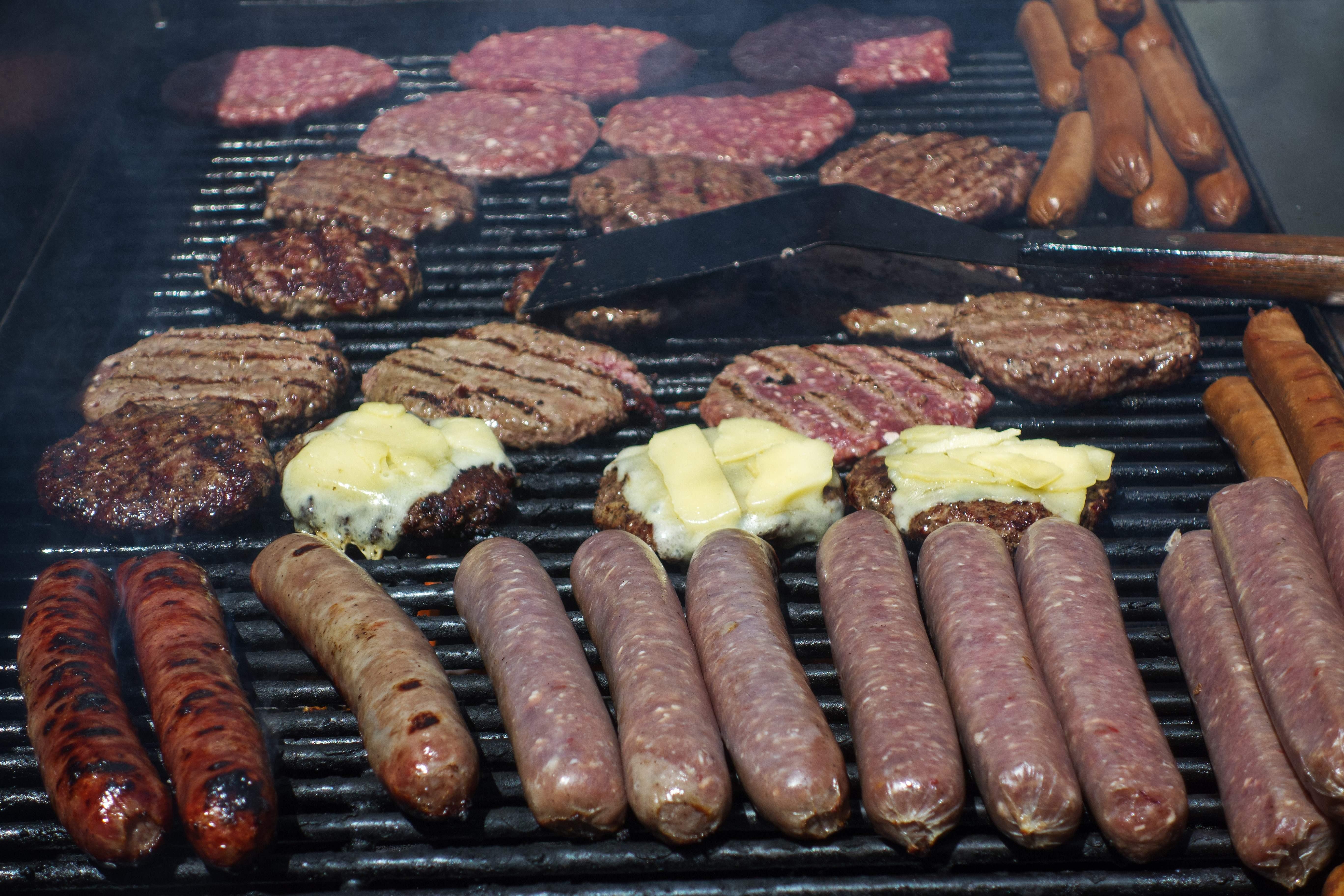 A grill with rows of hamburgers and sausages.