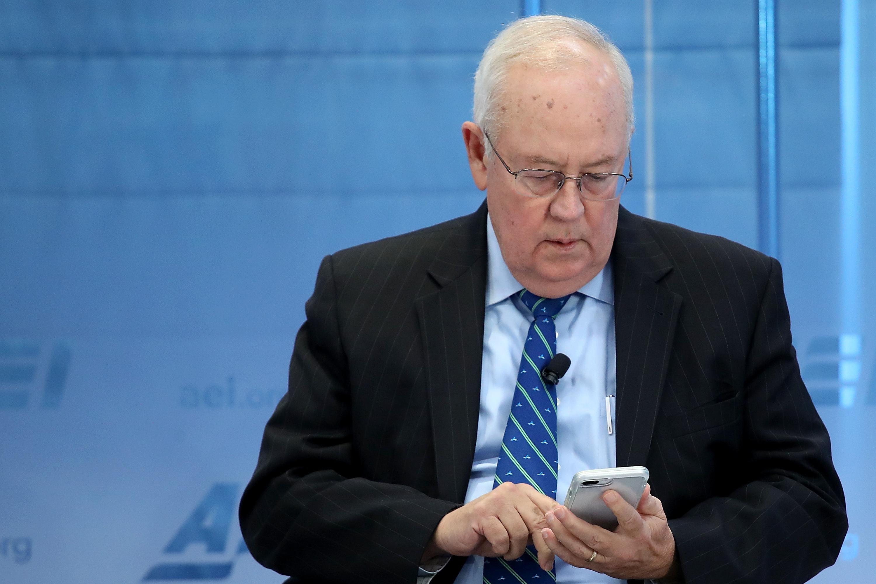Ken Starr looks down at his smartphone while onstage at an event.