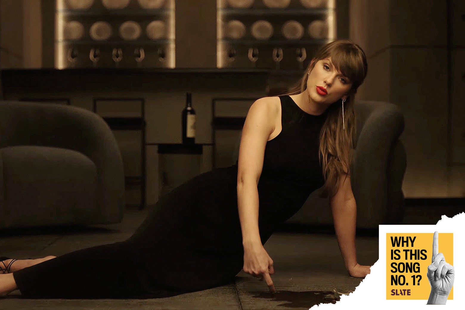 Taylor Swift, in a long black dress, lays across a carpet in a minimalist modern apartment, pointing down at some wine spilled on the floor below her. Over the bottom right corner of the image is placed a logo that reads "Why Is This Song No. 1?" and "Slate." 
