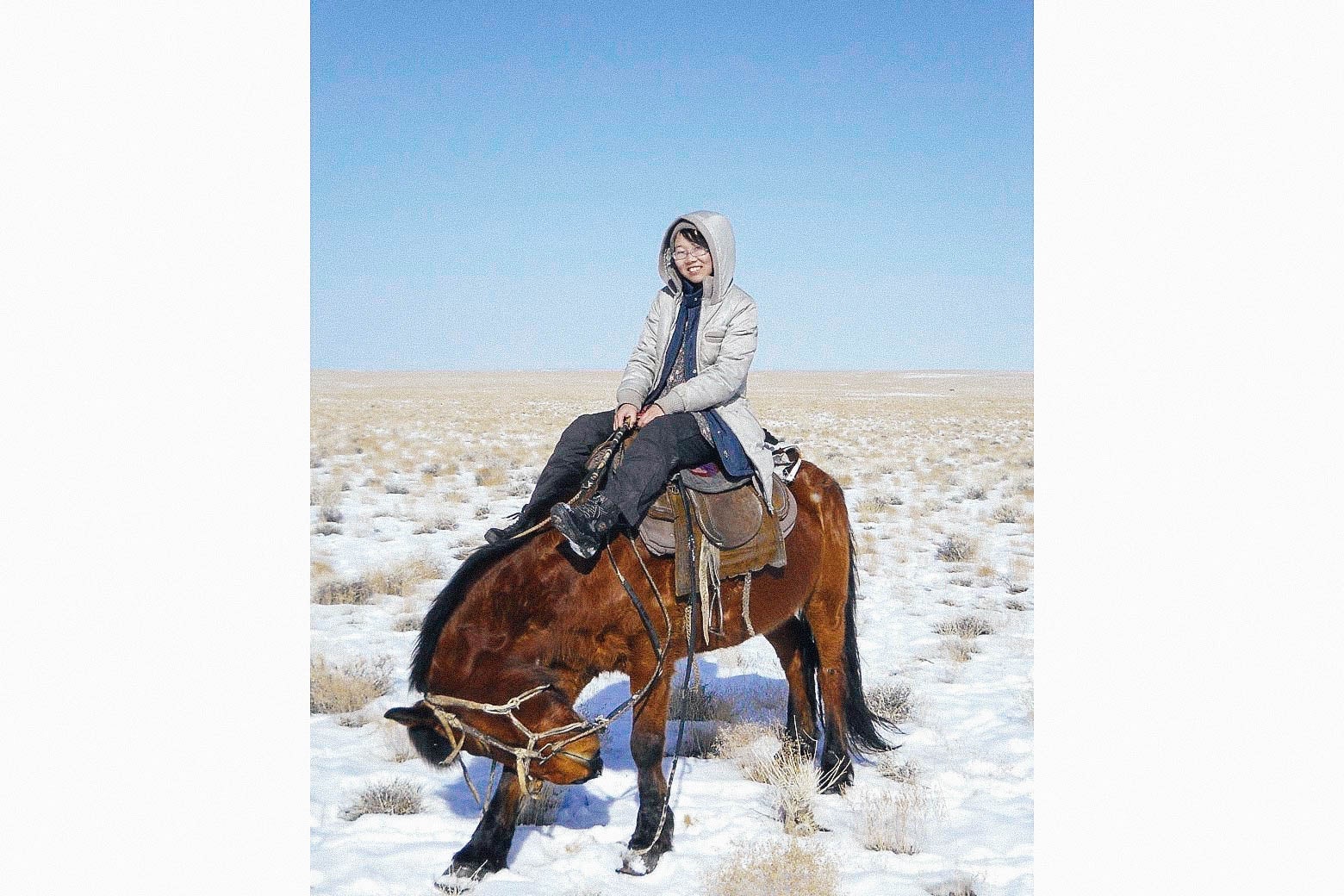 Li Juan on a horse in the snow-covered desert.