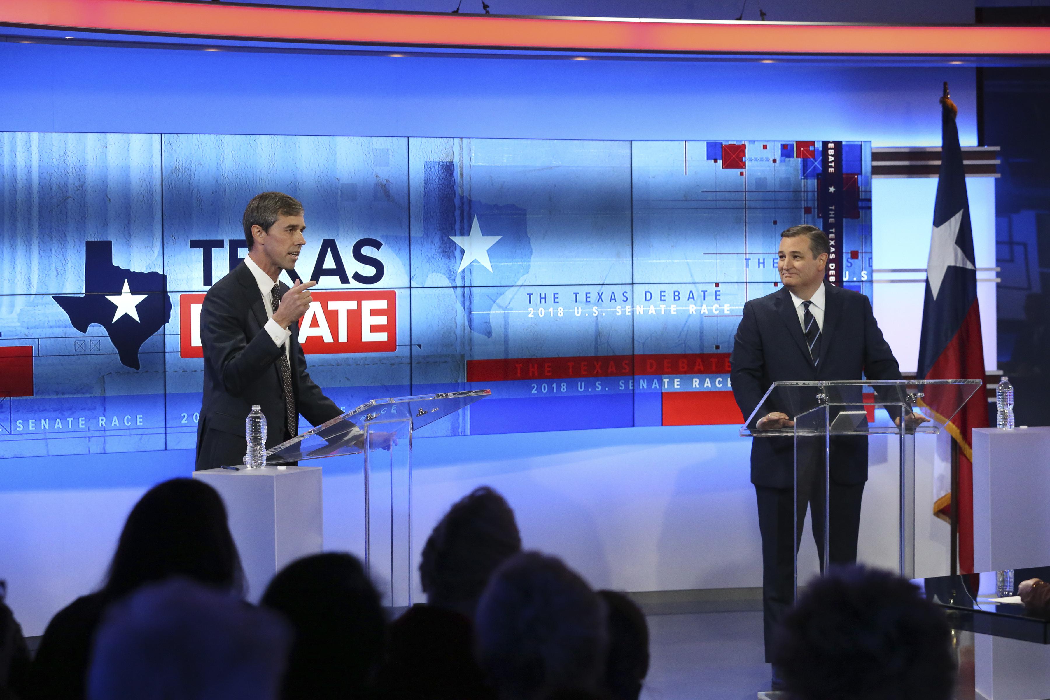 Rep. Beto O’Rourke and Sen. Ted Cruz stand at clear podiums onstage.